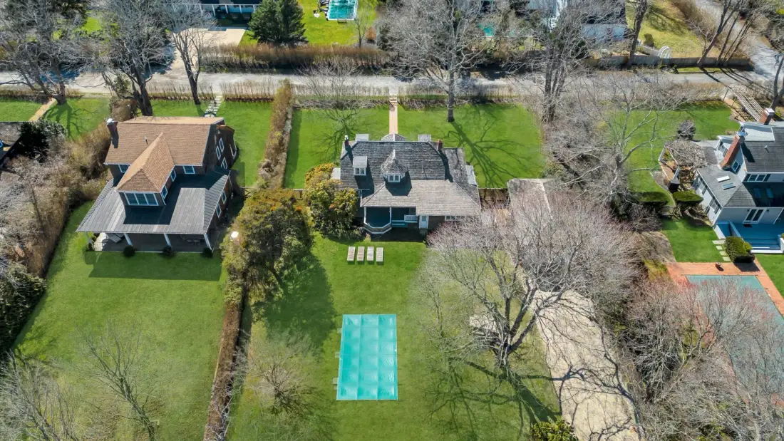 Aerial view of homes with green lawns and a turquoise rectangular pool.