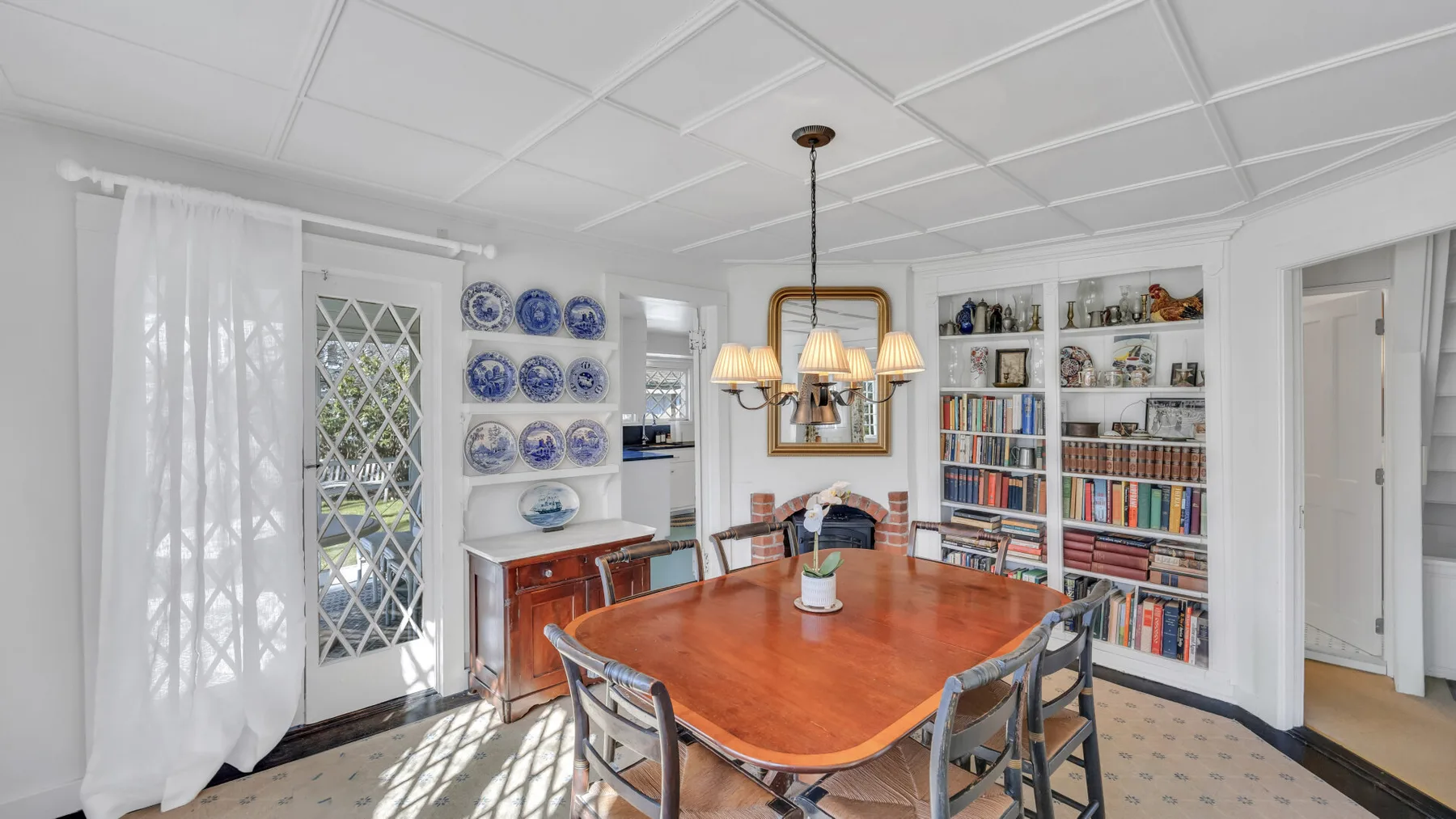 A dining room with a large wooden table, chairs, and bookshelves.