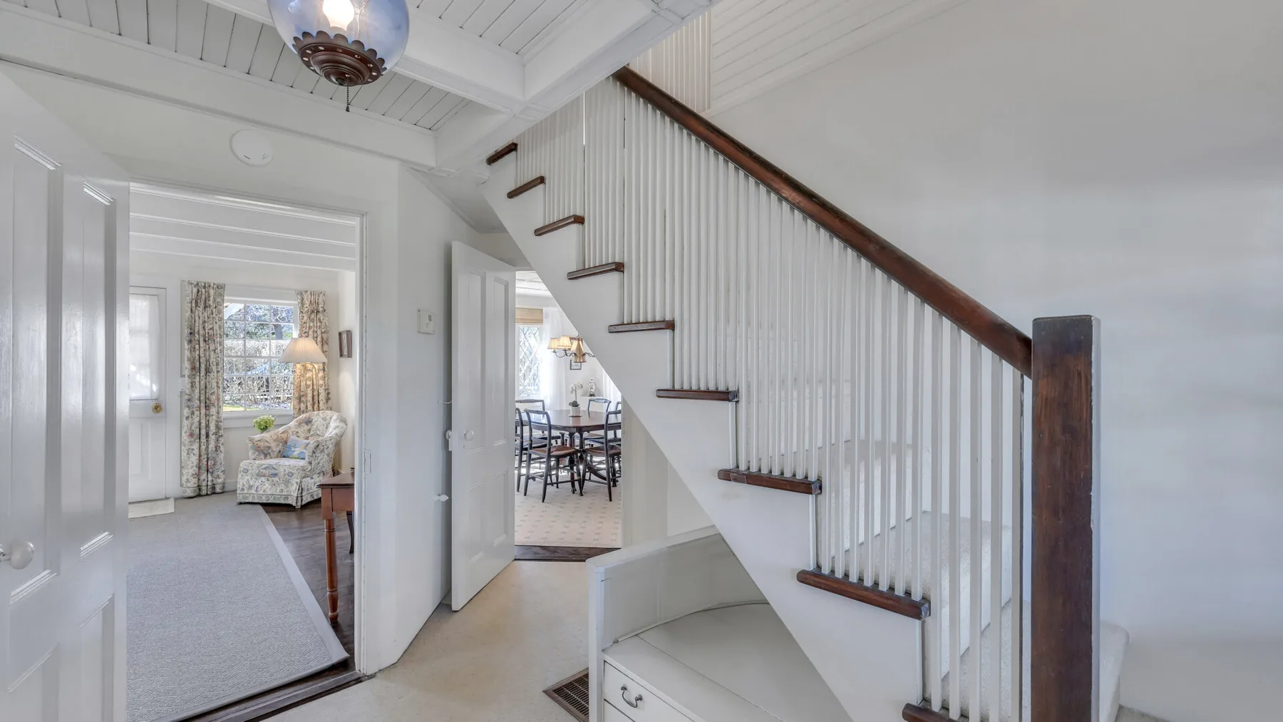 An interior hallway with a staircase and an open doorway to a dining area.