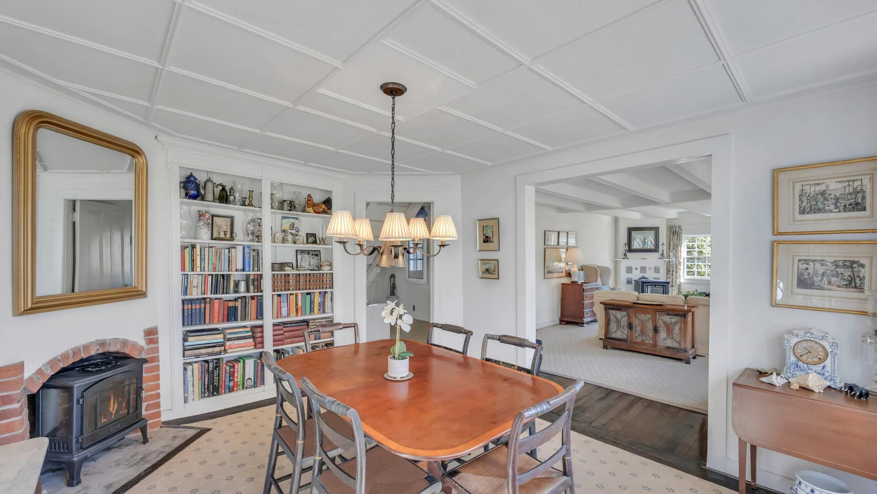 A dining room with a wooden table, bookshelves, and a fireplace.