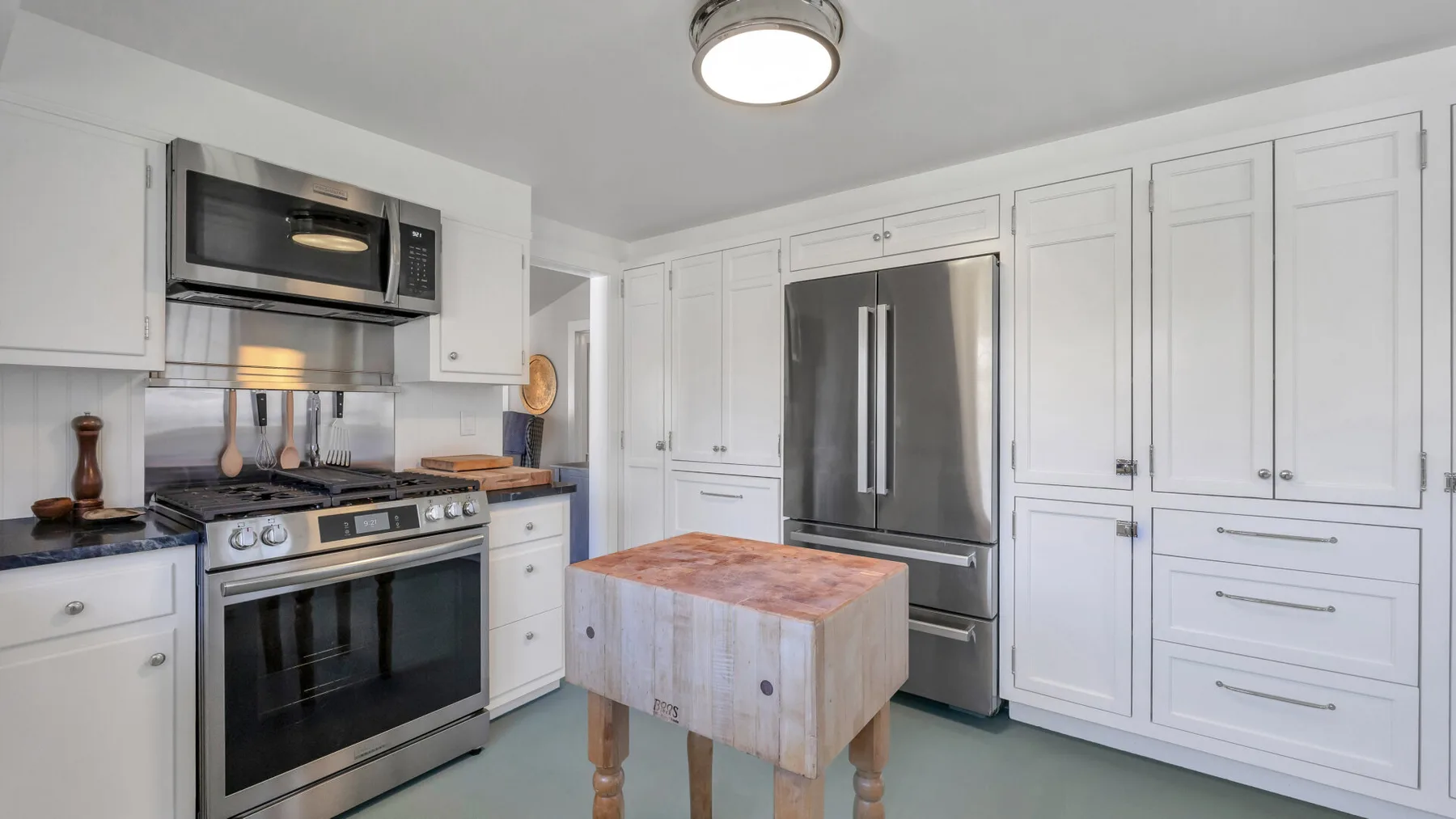 A bright kitchen with white cabinets, stainless steel appliances, and a central island.