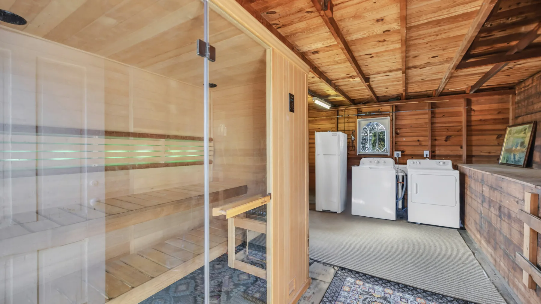 A wooden sauna sits beside laundry appliances in a timber-paneled room.