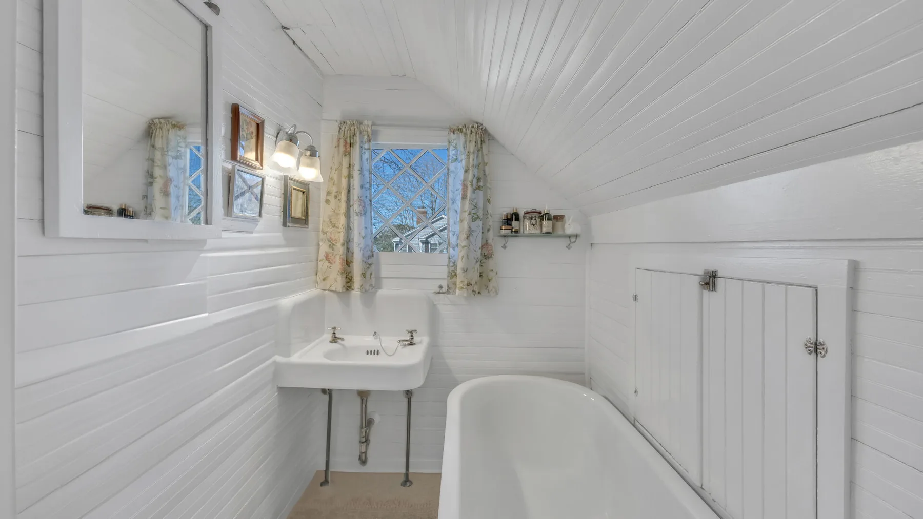 A bright bathroom with a bathtub, wall-mounted sink, and window.