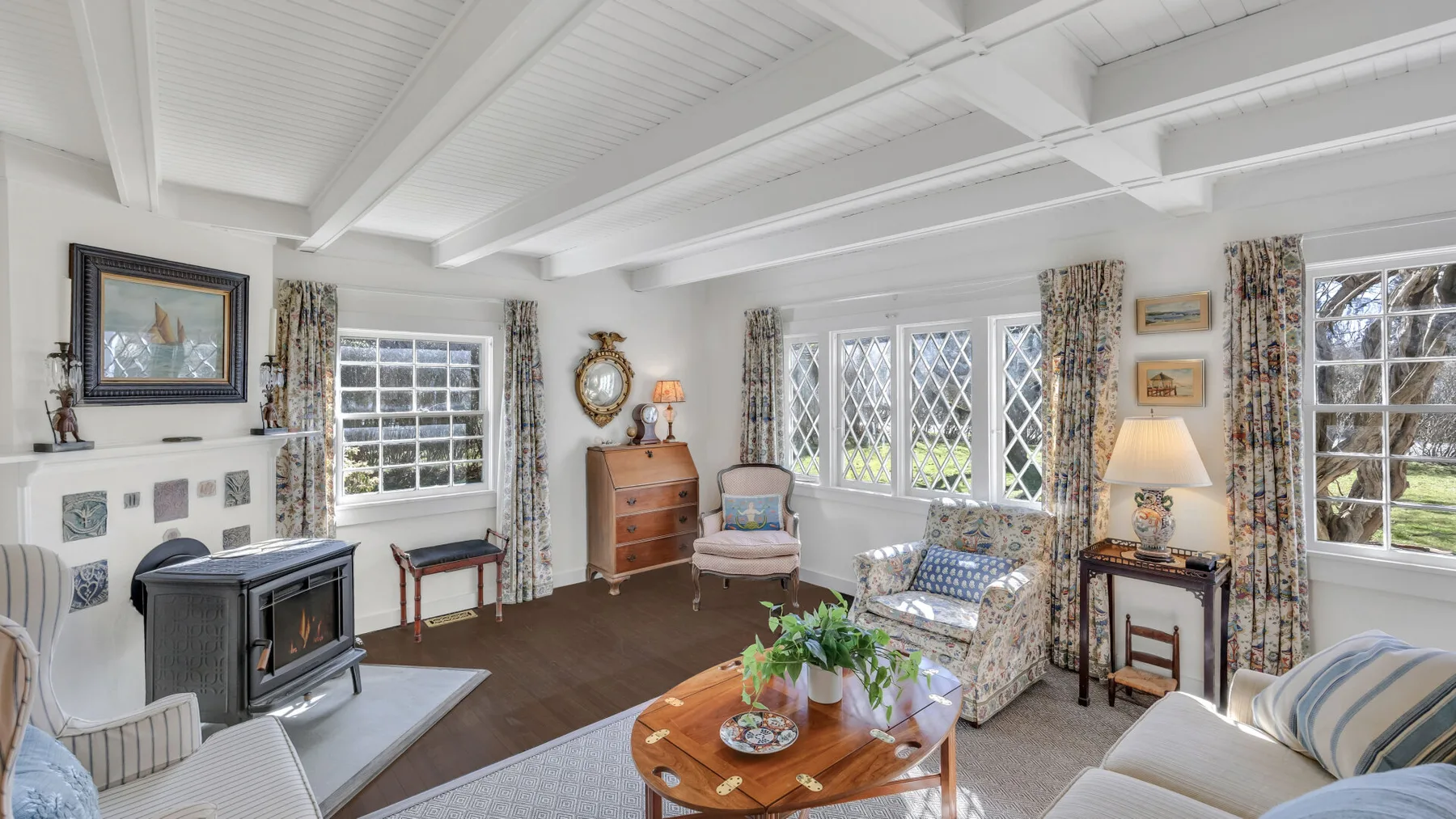 A bright living room with patterned seating and a wood-burning stove.