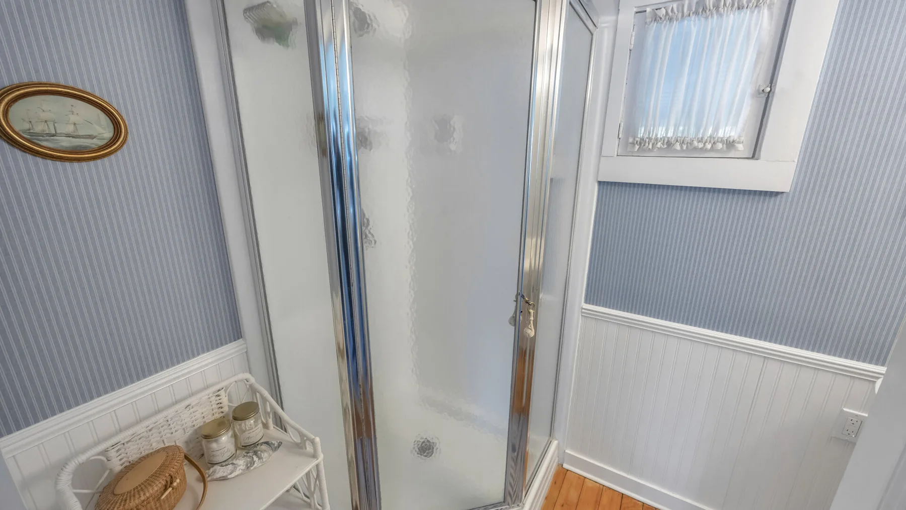 A bathroom shower with blue-gray paneled walls and white trim.