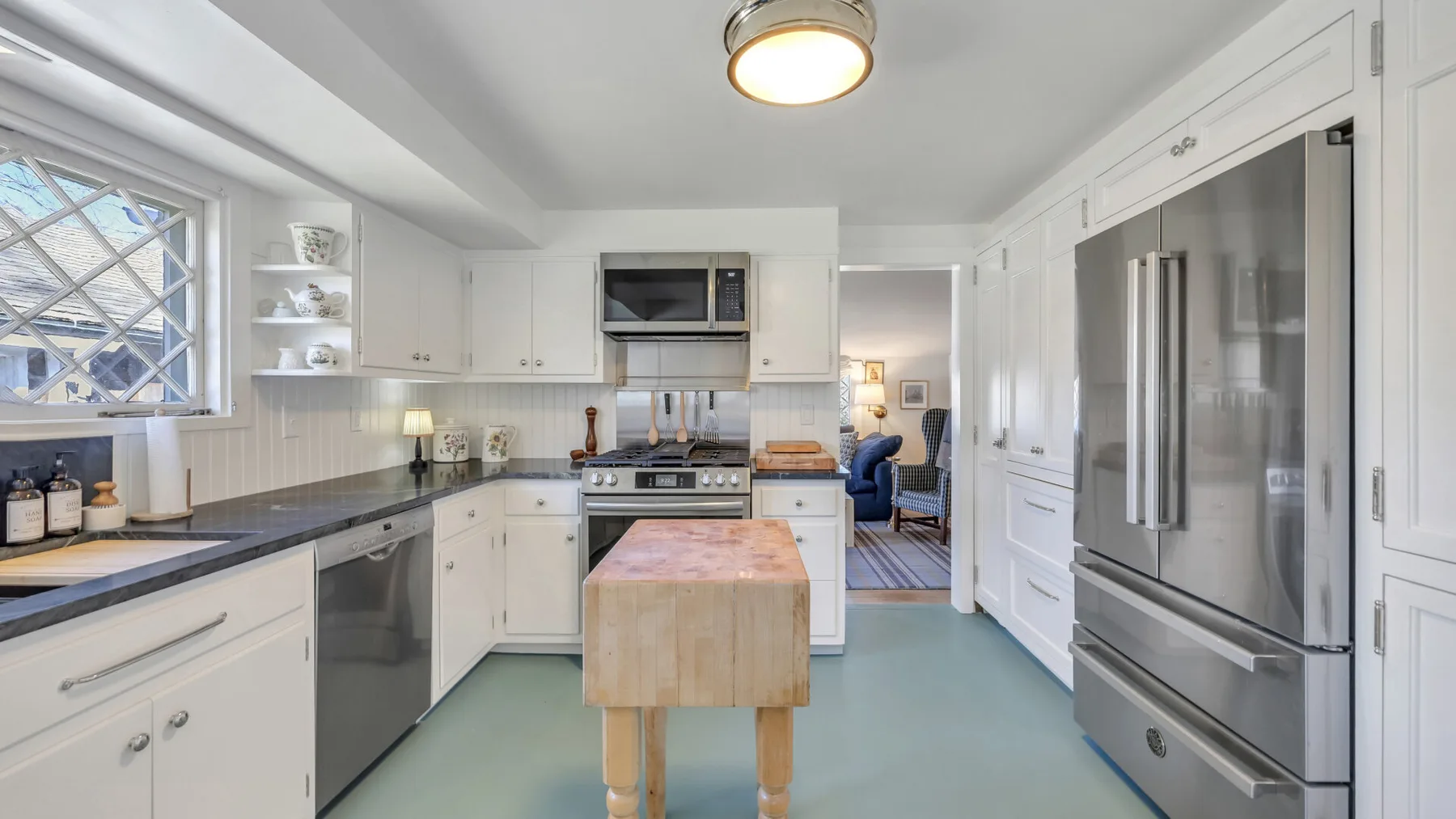 A bright kitchen with white cabinets, stainless steel appliances, and a central island.