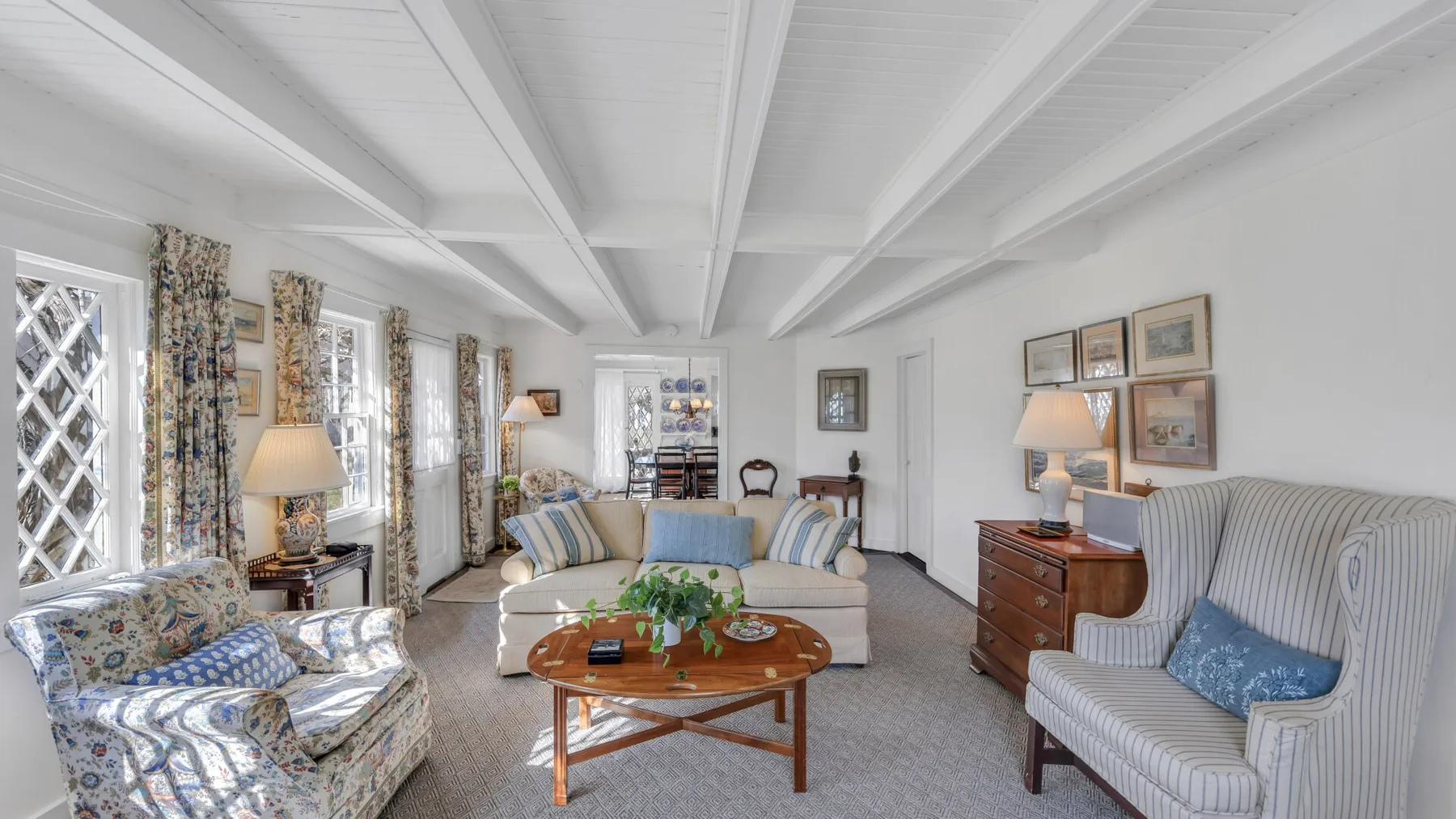 A bright living room with patterned seating and a wooden coffee table.