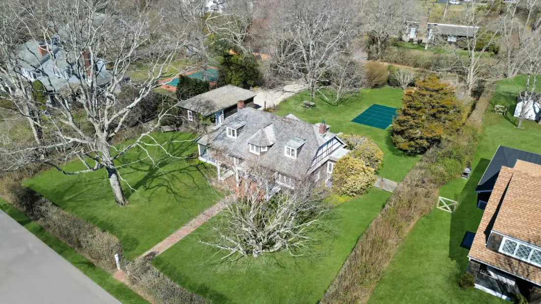 An aerial view of a large house surrounded by lawns and trees.
