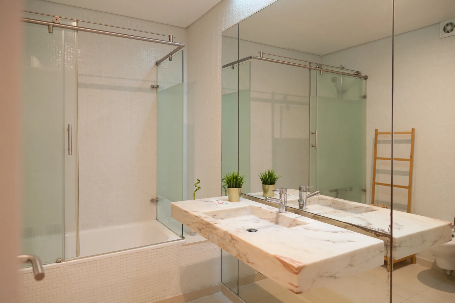 Un baño con una ducha de vidrio y un amplio lavabo de mármol.