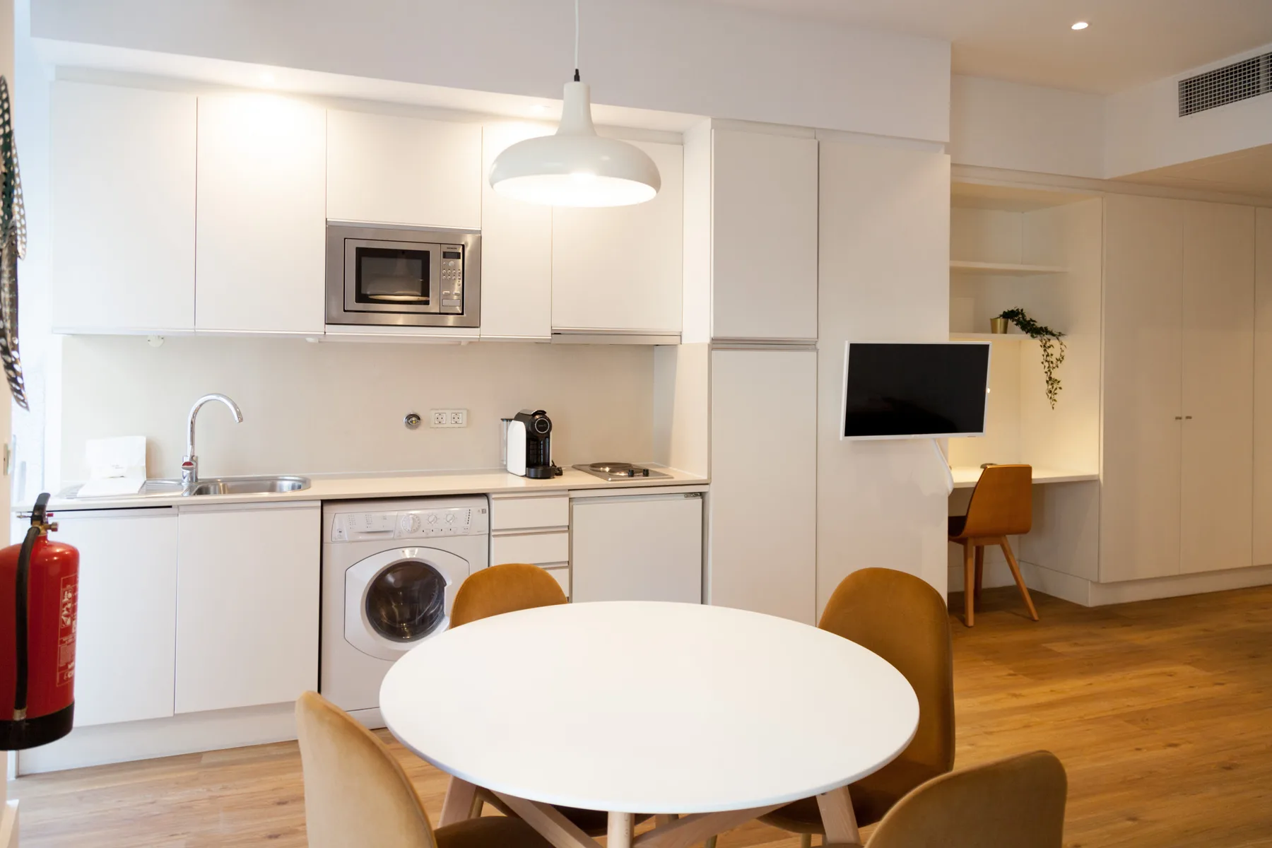 Una cocina compacta con zona de comedor, mesa redonda y electrodomésticos integrados.