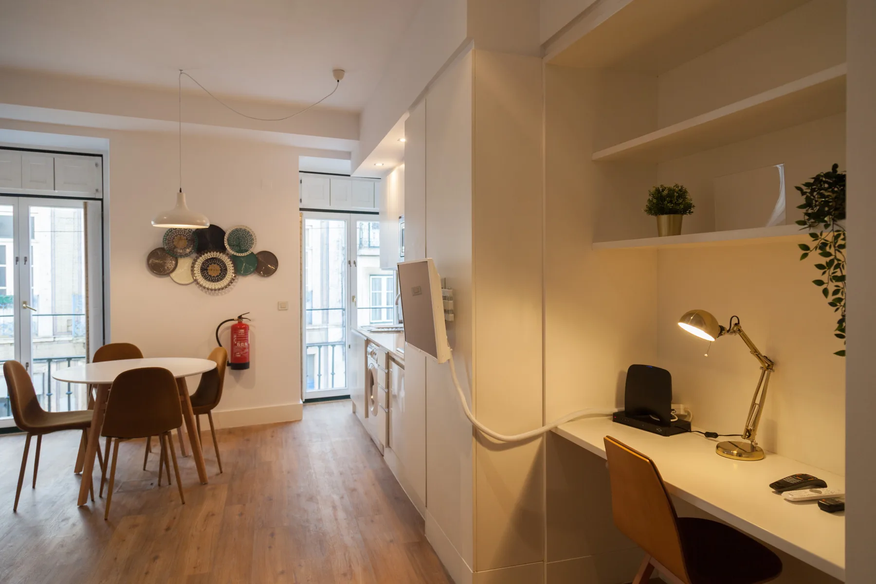 Un estudio luminoso combina una zona de comedor con un escritorio y estanterías.