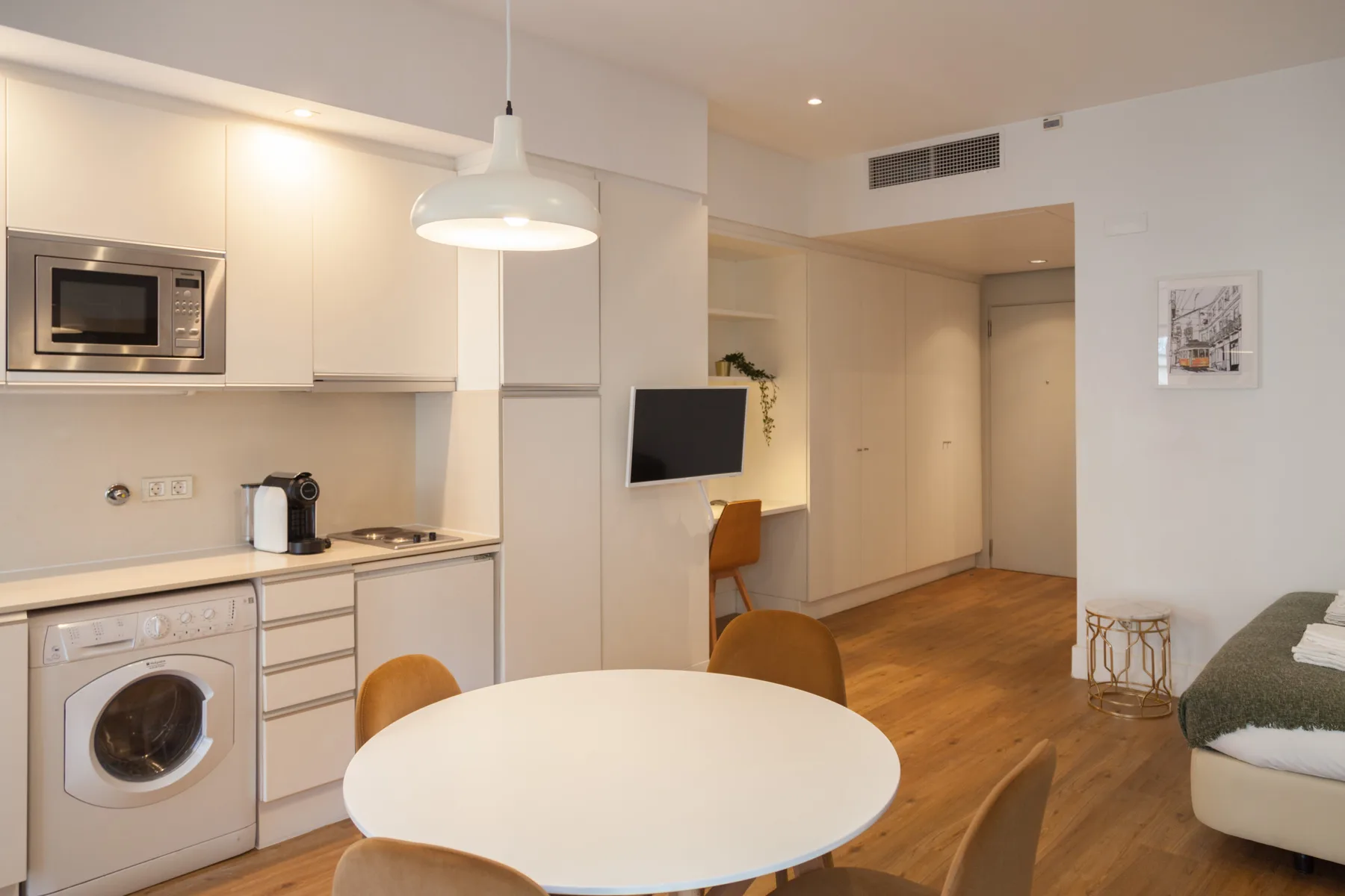 Interior de estudio compacto con cocina pequeña, mesa de comedor y zona de descanso.