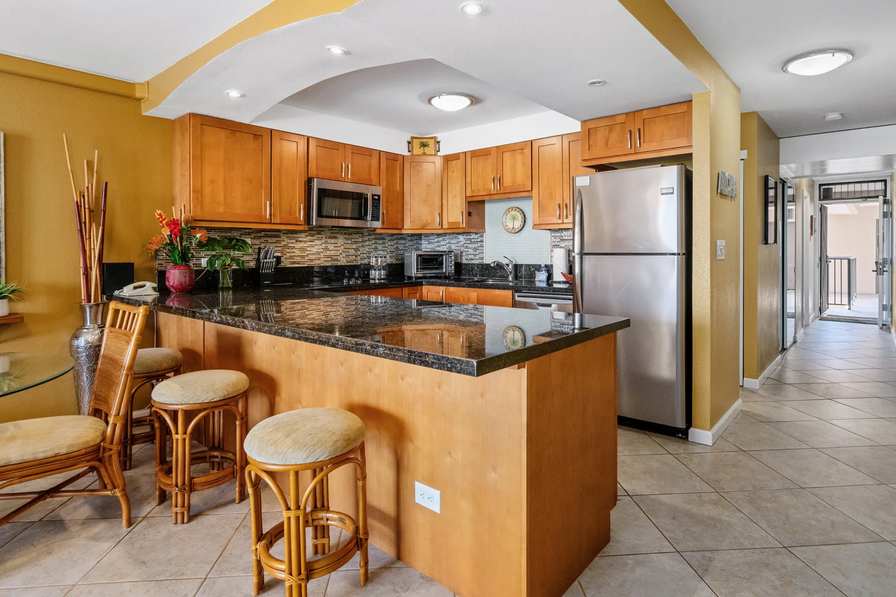 A kitchen with a central counter, wooden cabinets, and stainless steel appliances.