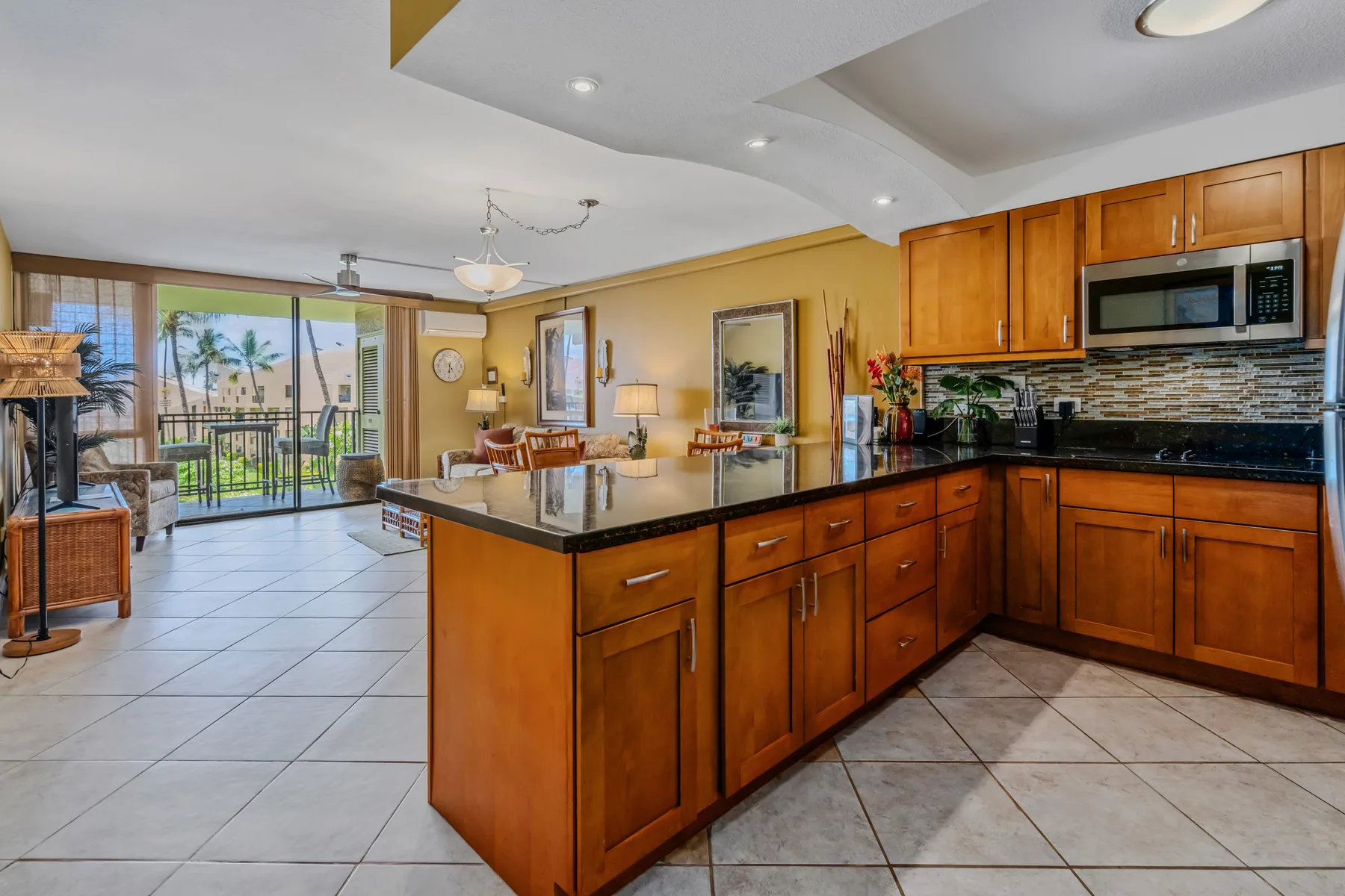An open kitchen with a central island looks onto a dining and living area.