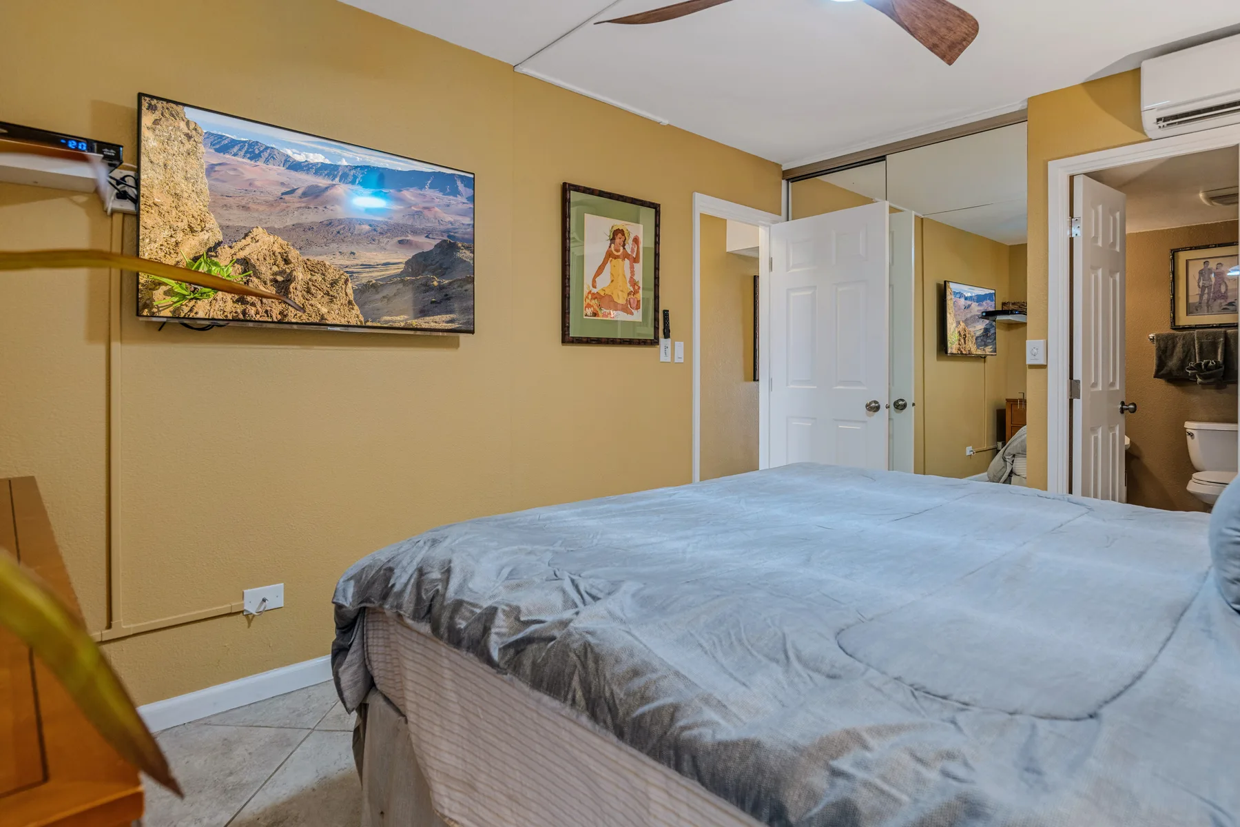 A bedroom with a large bed, wall art, and an open doorway.