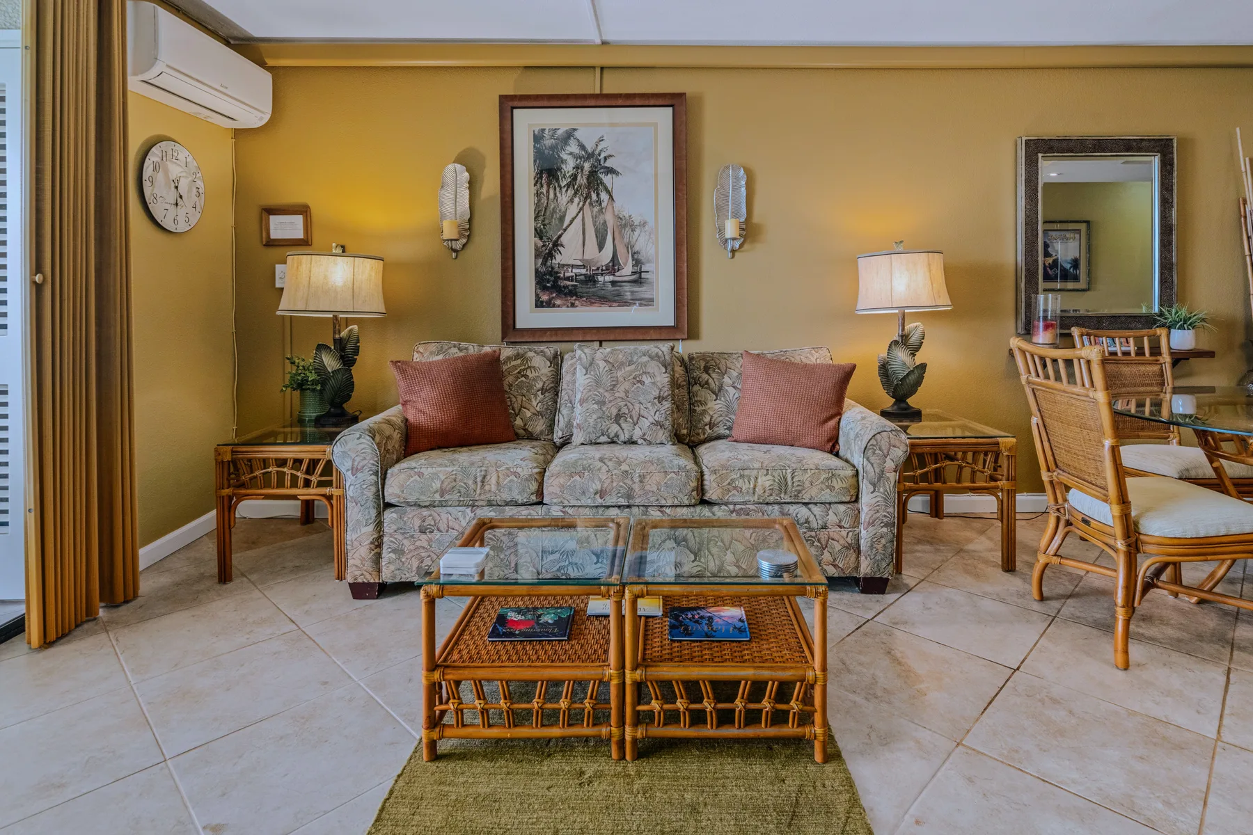 A living room with a patterned sofa, wicker coffee table, and dining area.