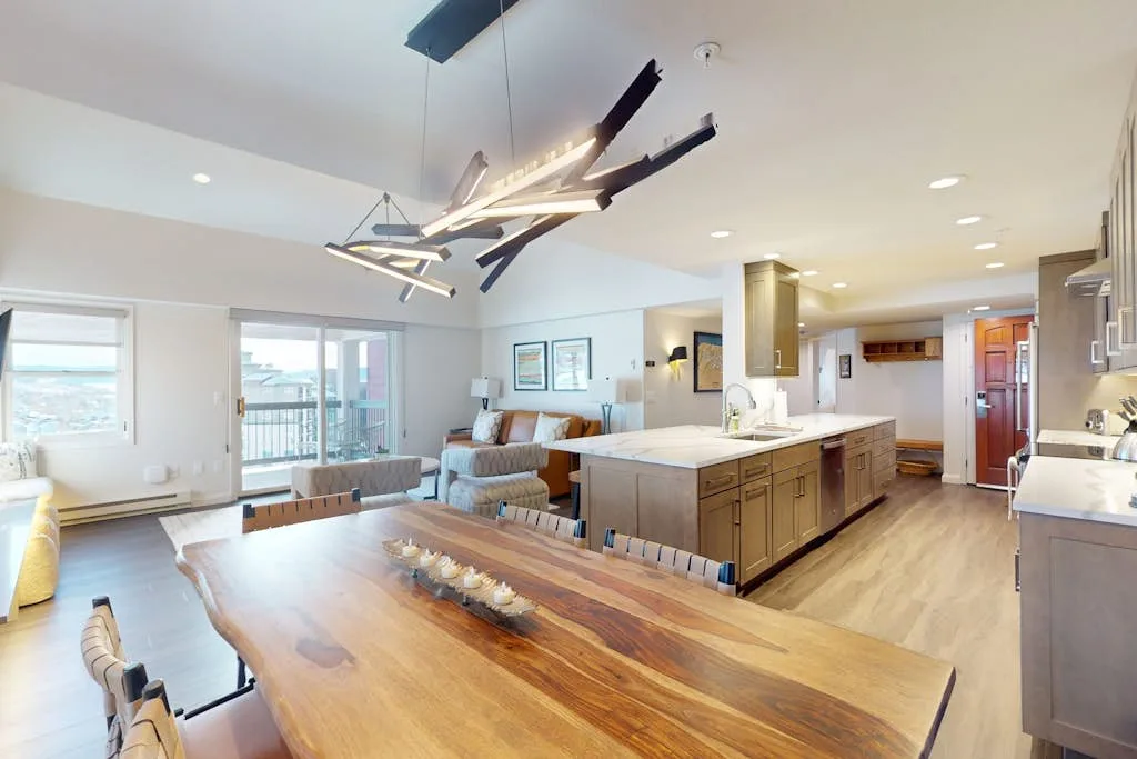 Una luminosa cocina-comedor de planta abierta con una gran mesa de madera e isla.
