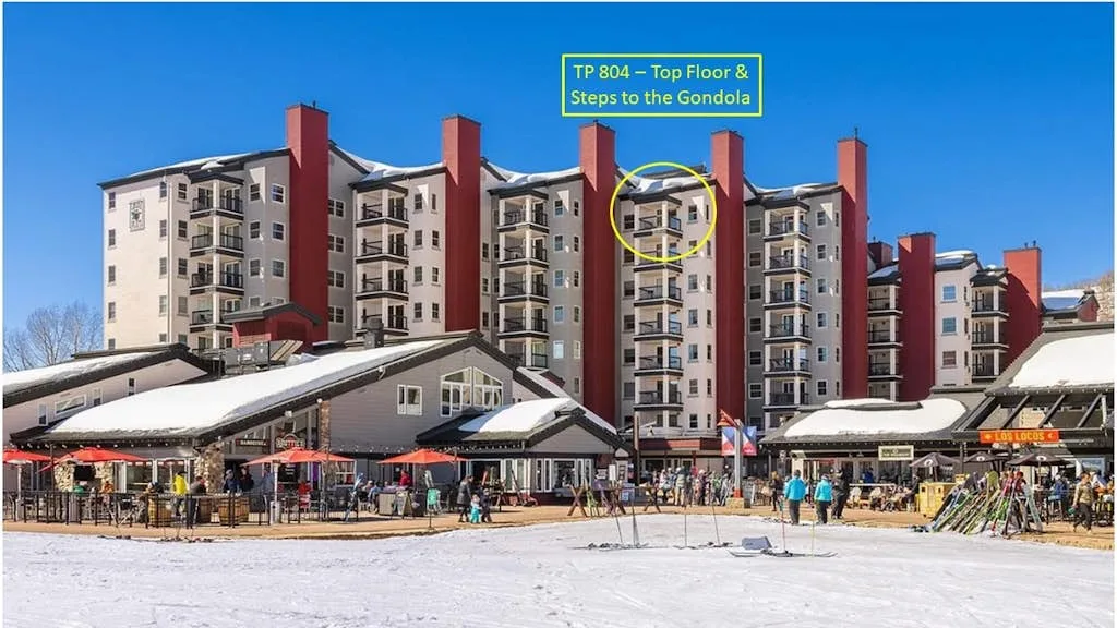 Un edificio de varias plantas se alza junto a una plaza exterior cubierta de nieve.