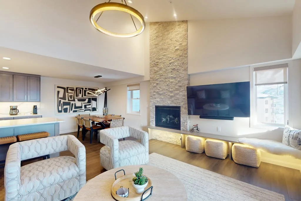 Una luminosa sala de estar de planta abierta con asientos, una mesa de comedor y un televisor en la pared.