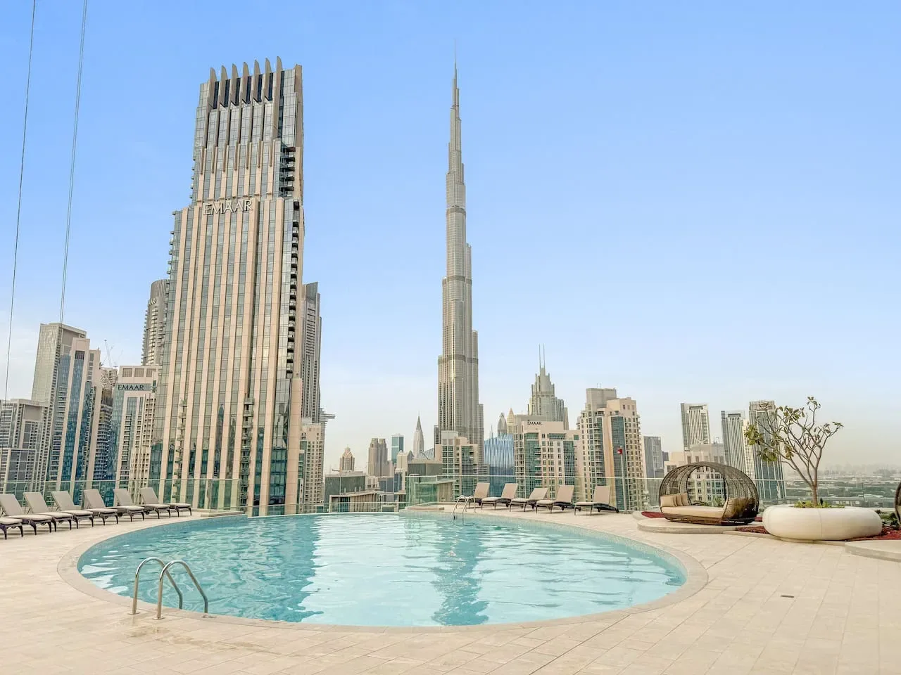A rooftop pool overlooks a city skyline with a tall spired tower.