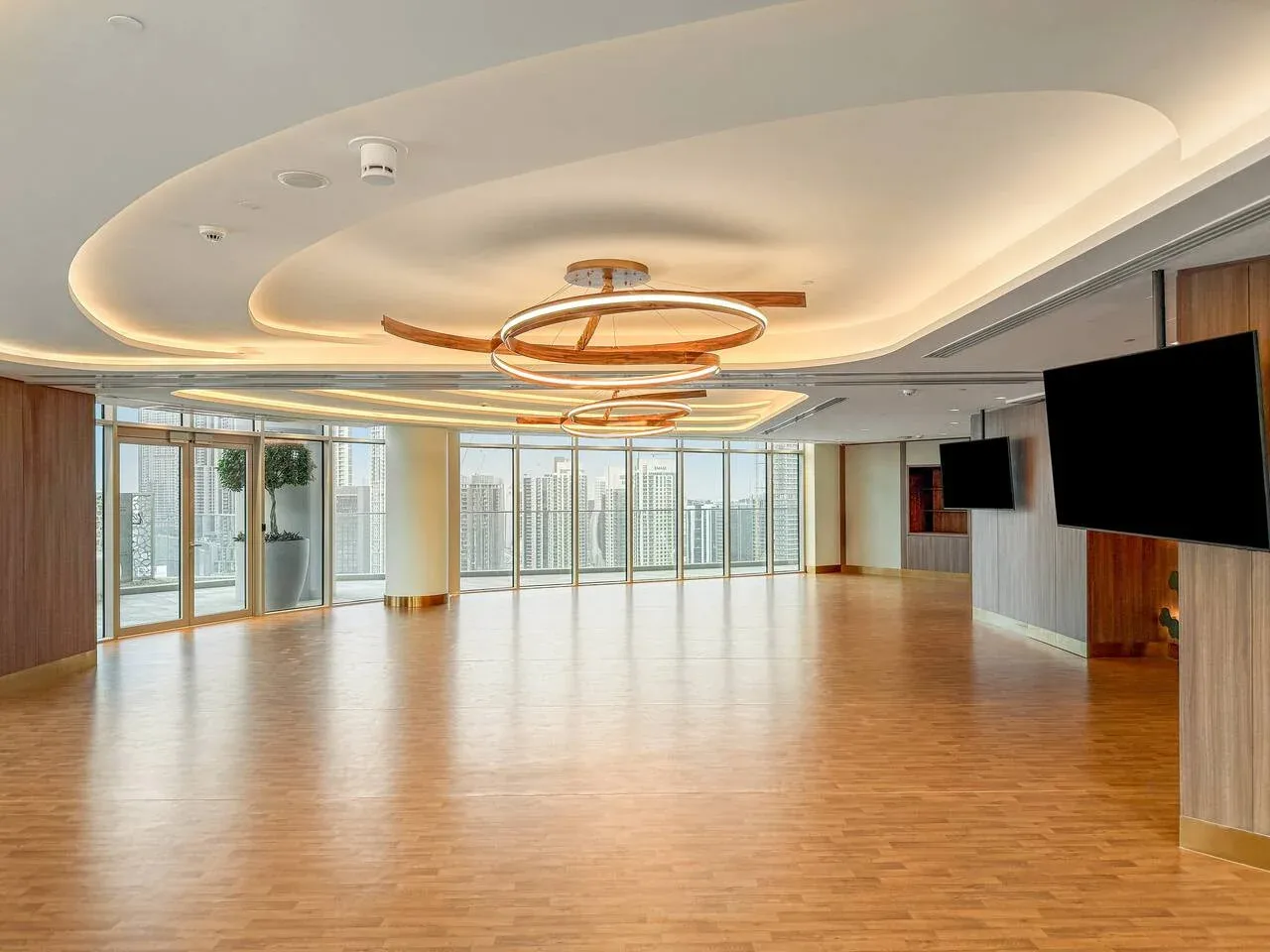 A spacious, brightly lit room with wood flooring and large windows.