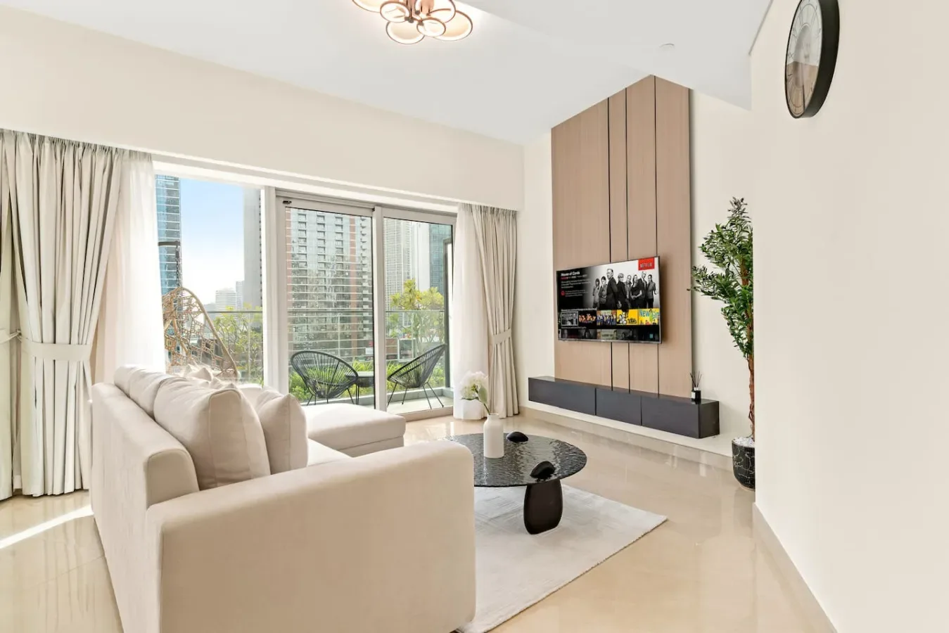 A bright living room with seating, a television, and large windows.