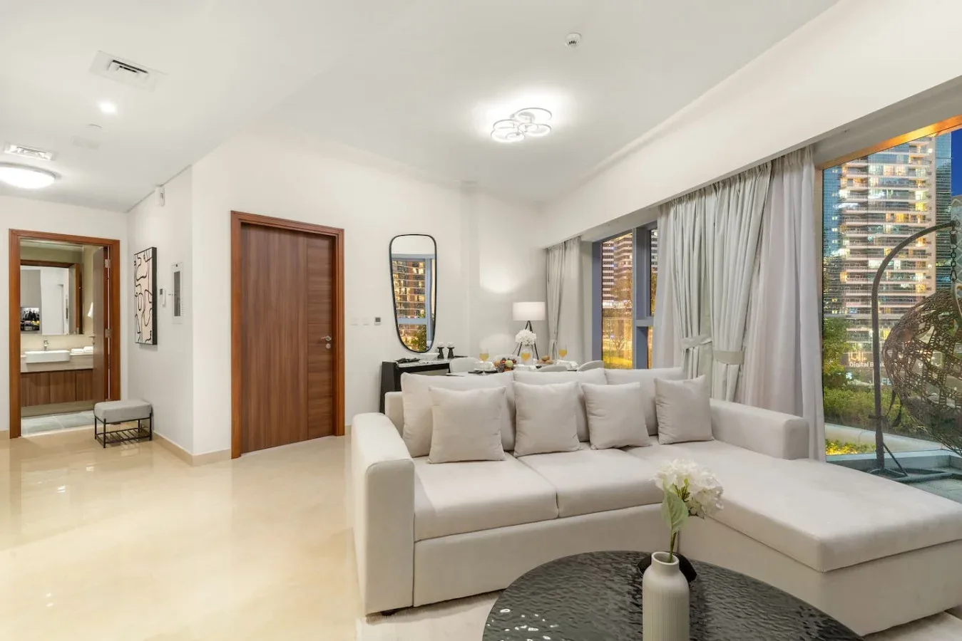 A bright living room with pale seating beside large windows.