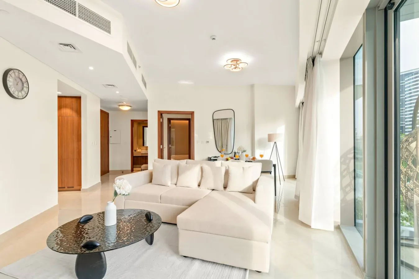 A bright living room with a white sectional and floor-to-ceiling windows.