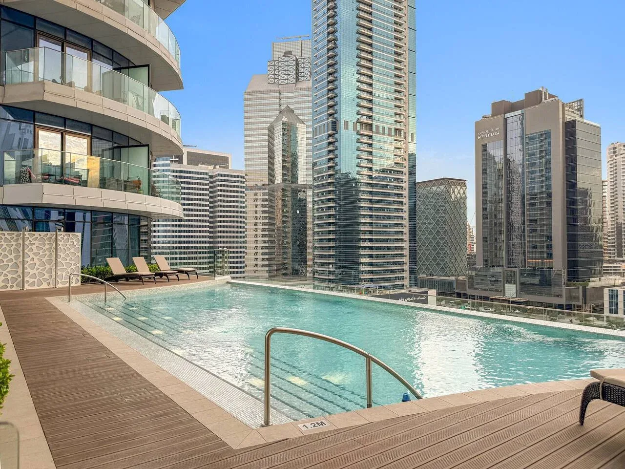 A rooftop swimming pool and deck overlook a cluster of high-rise buildings.
