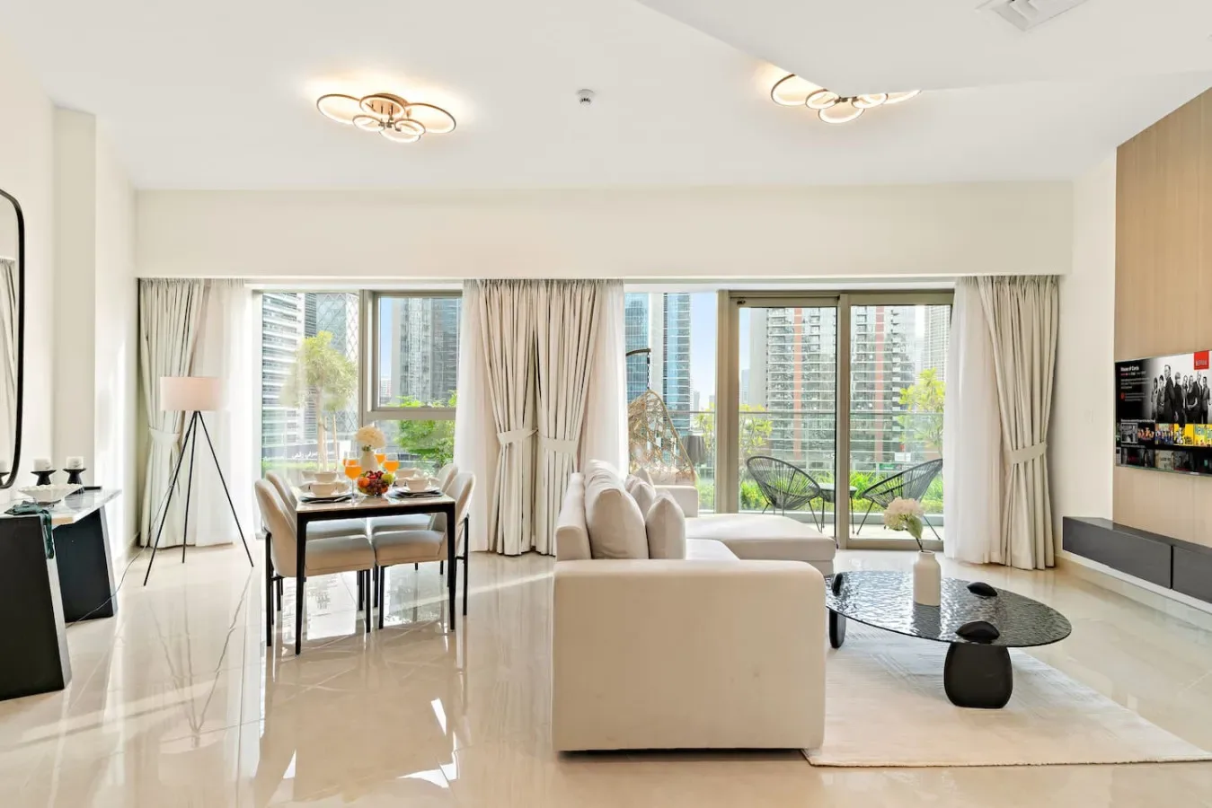 A bright living room with seating, a dining table, and large windows.