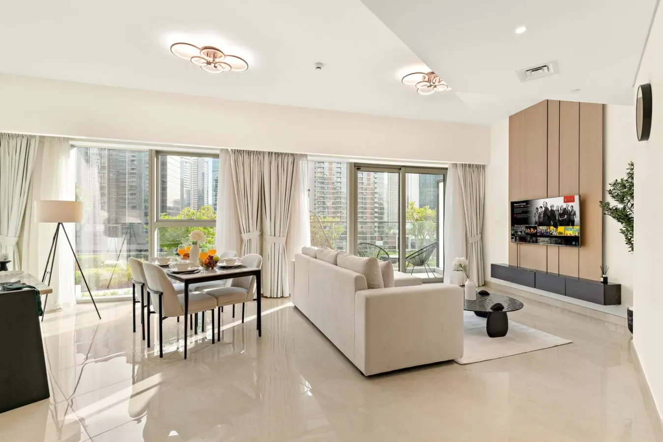 A bright living and dining area with seating, a table, and large windows.