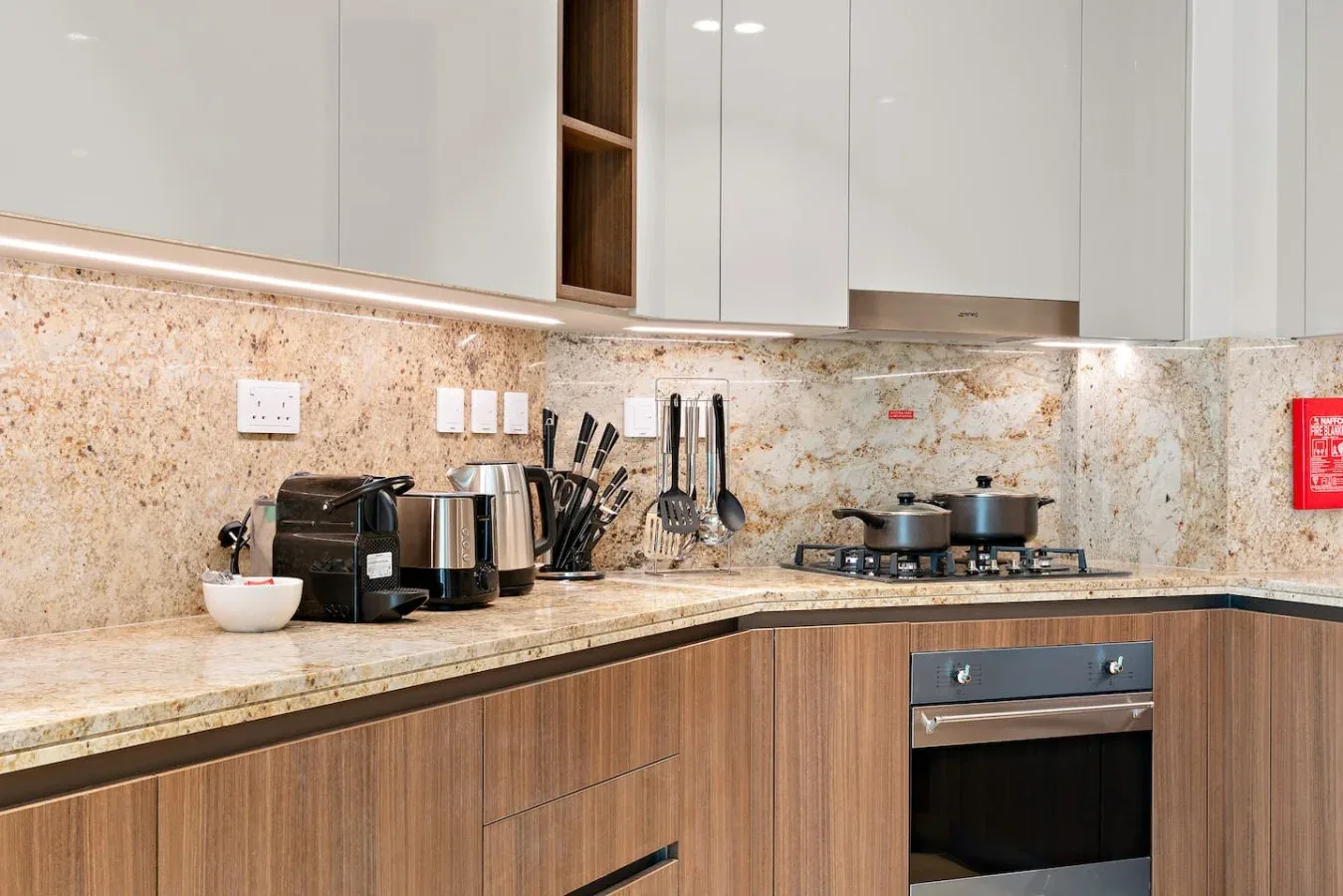 A modern kitchen with wood-front cabinets, countertop appliances, and a stovetop.