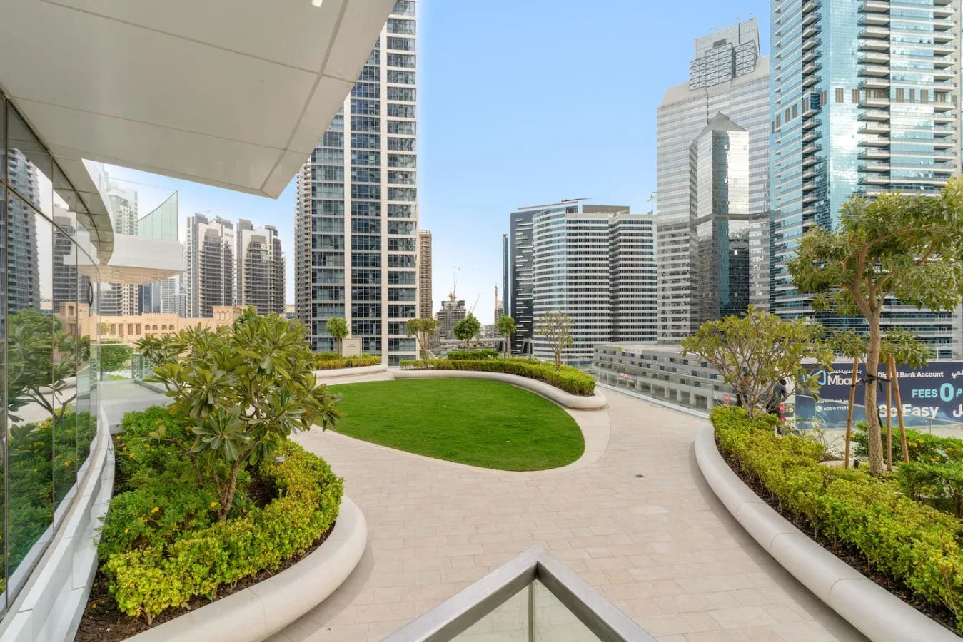 A landscaped rooftop terrace with curved garden beds and city buildings beyond.