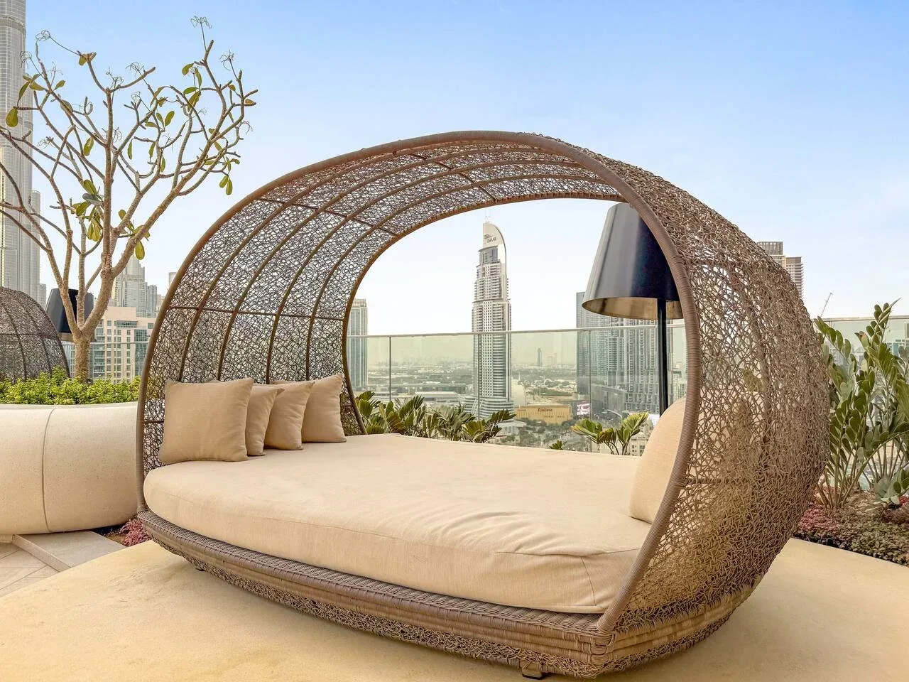 A rooftop terrace seating area with a curved woven canopy and city views.