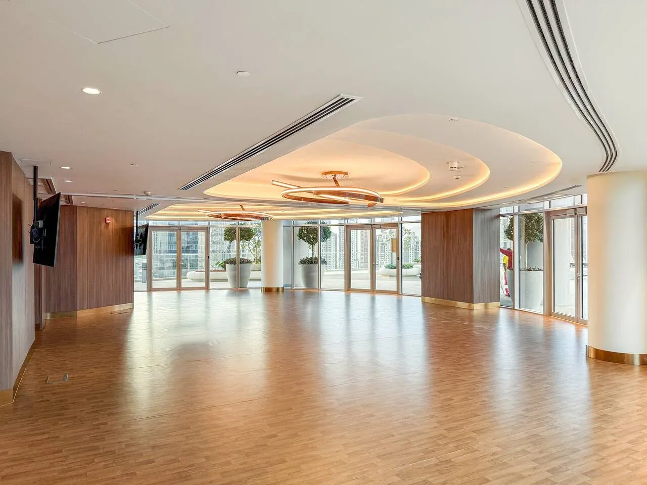A spacious indoor hall with wood flooring and large windows.