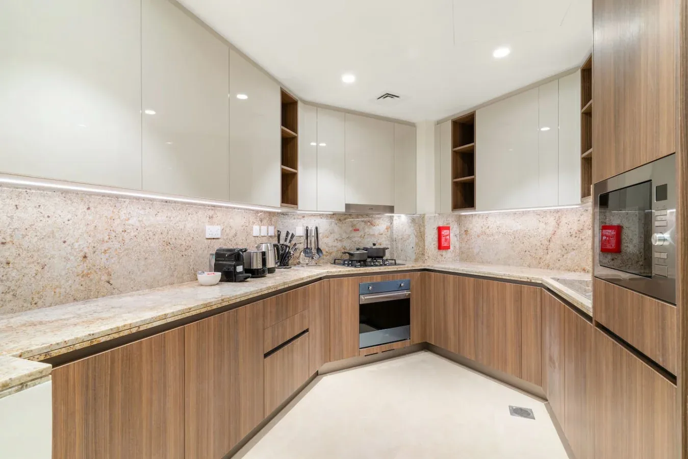 A modern kitchen with wood cabinetry, pale countertops, and built-in appliances.