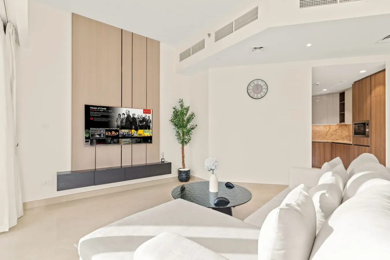 A bright living room with a television, seating, and a small dining table.