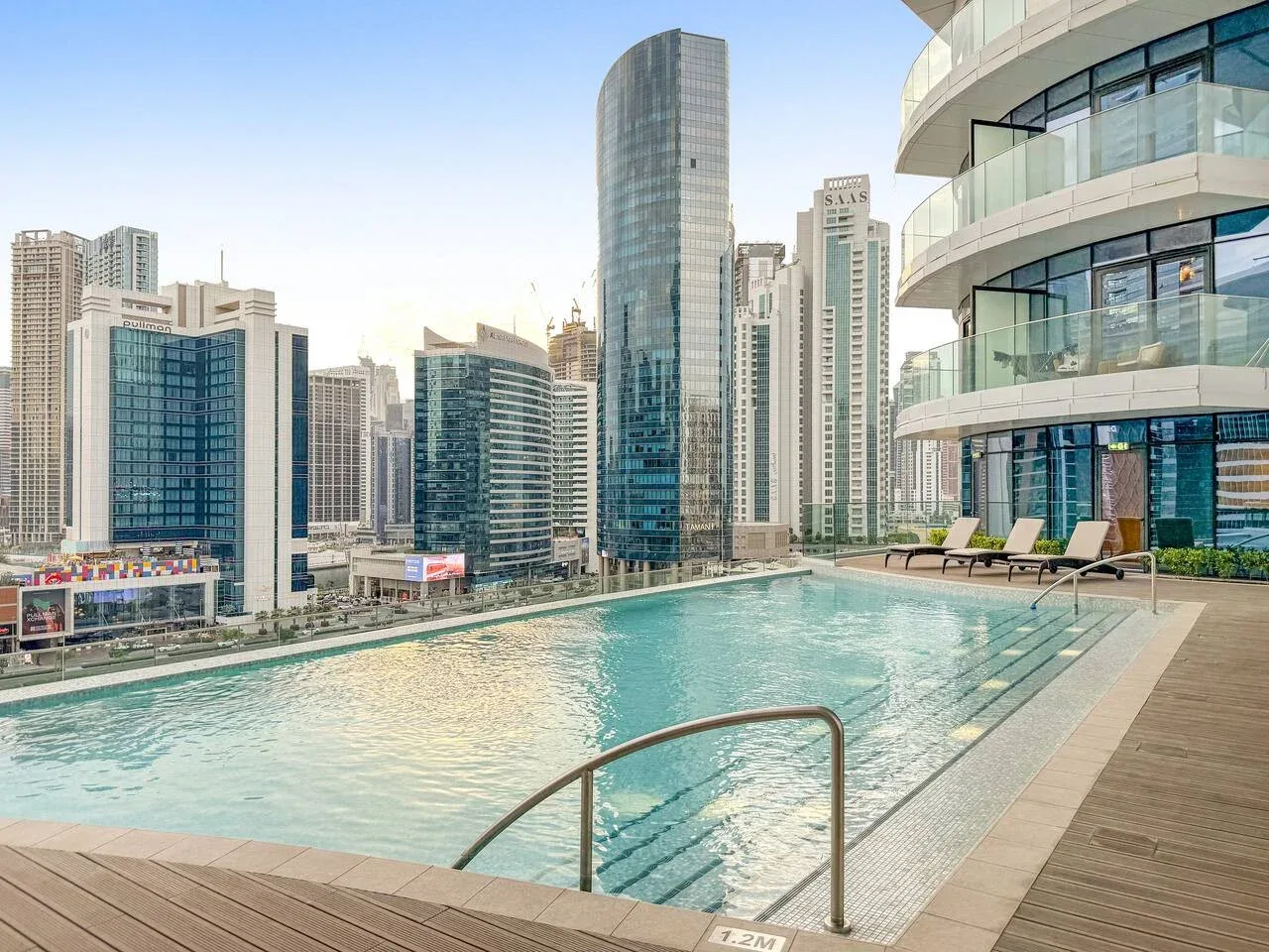 A rooftop swimming pool overlooks a cluster of modern high-rise buildings.