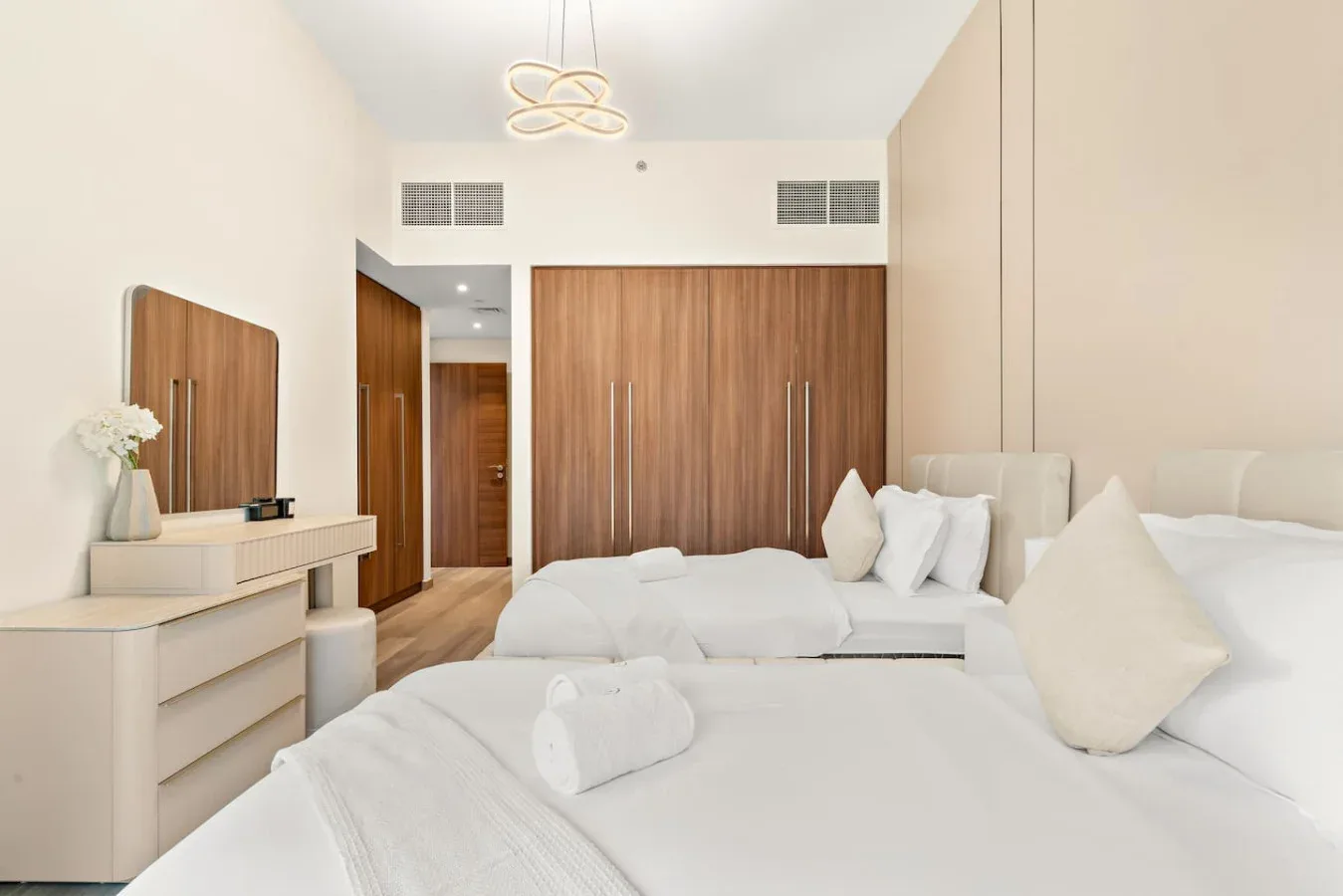 A bright bedroom with white bedding and wooden closet doors.