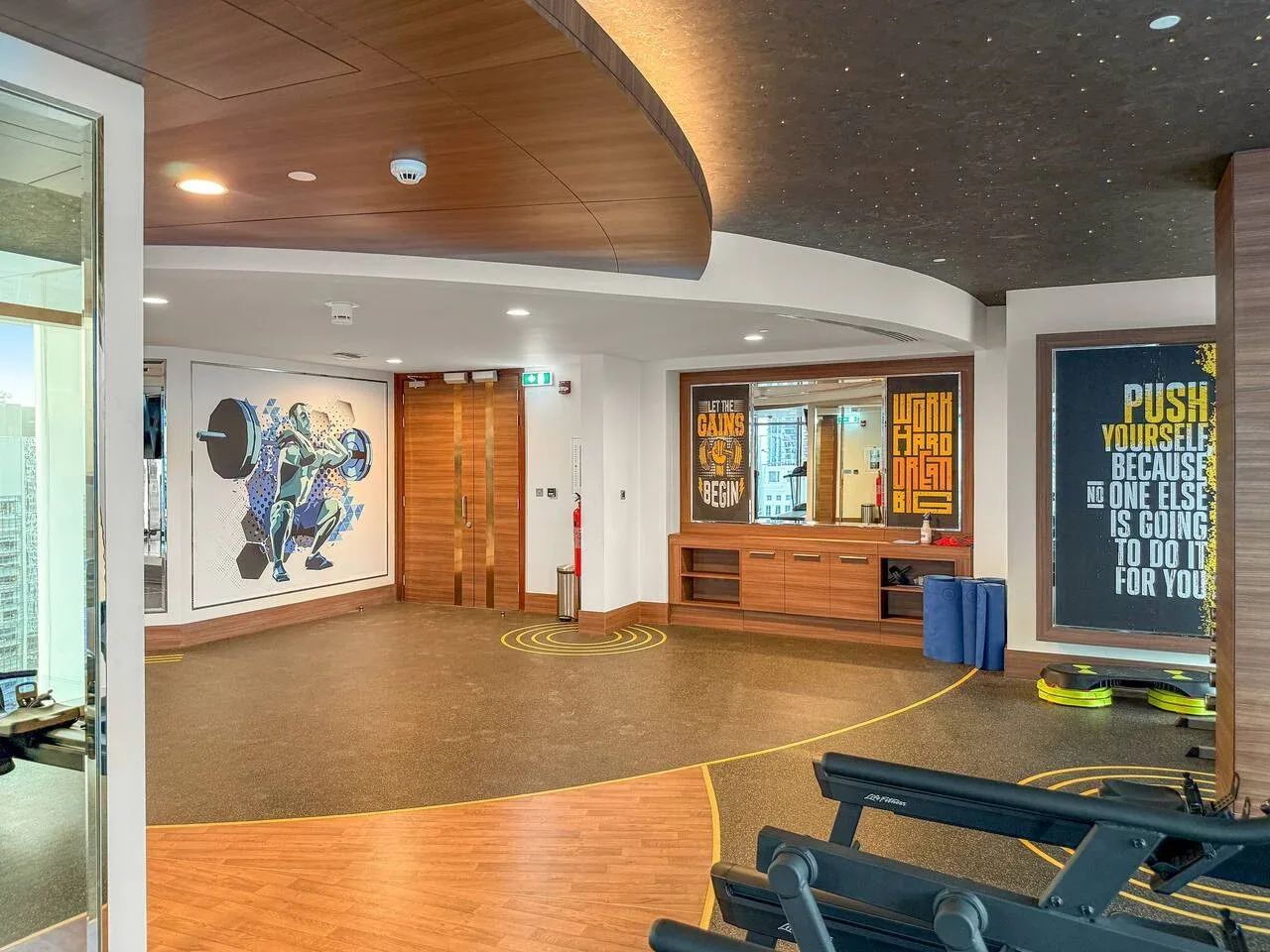 A modern lobby features colorful wall art and a curved wooden ceiling.