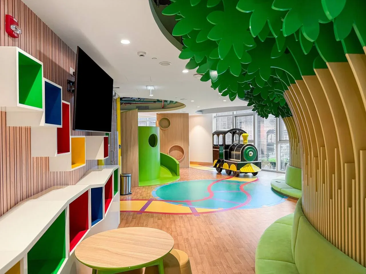A colorful indoor play area features a small train and a bright floor.