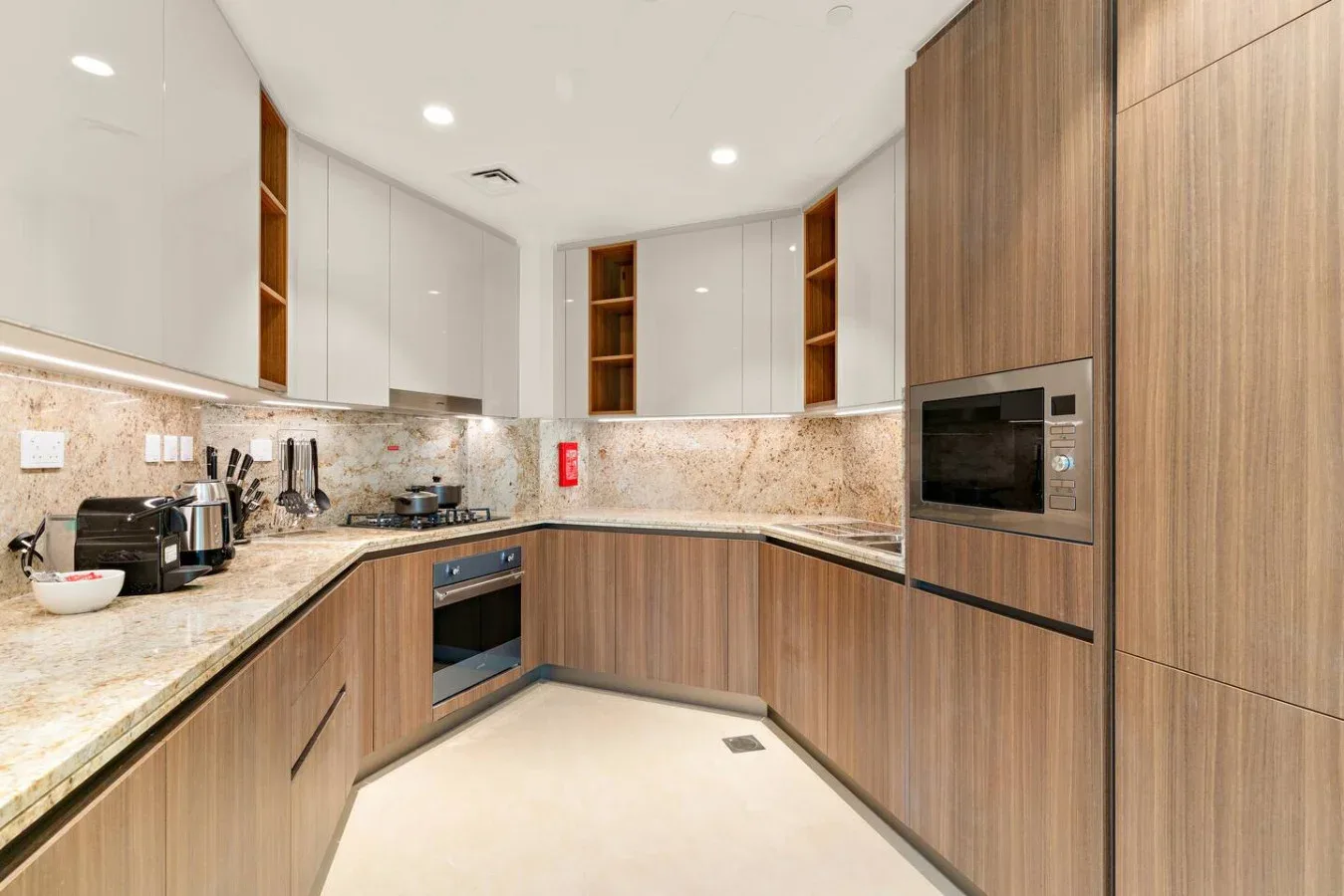A modern kitchen with wood cabinetry, stone counters, and built-in appliances.