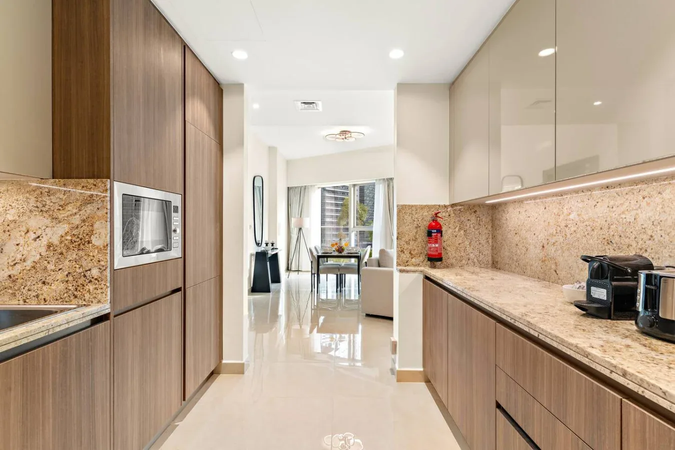A modern kitchen with stone countertops opens onto a dining area.