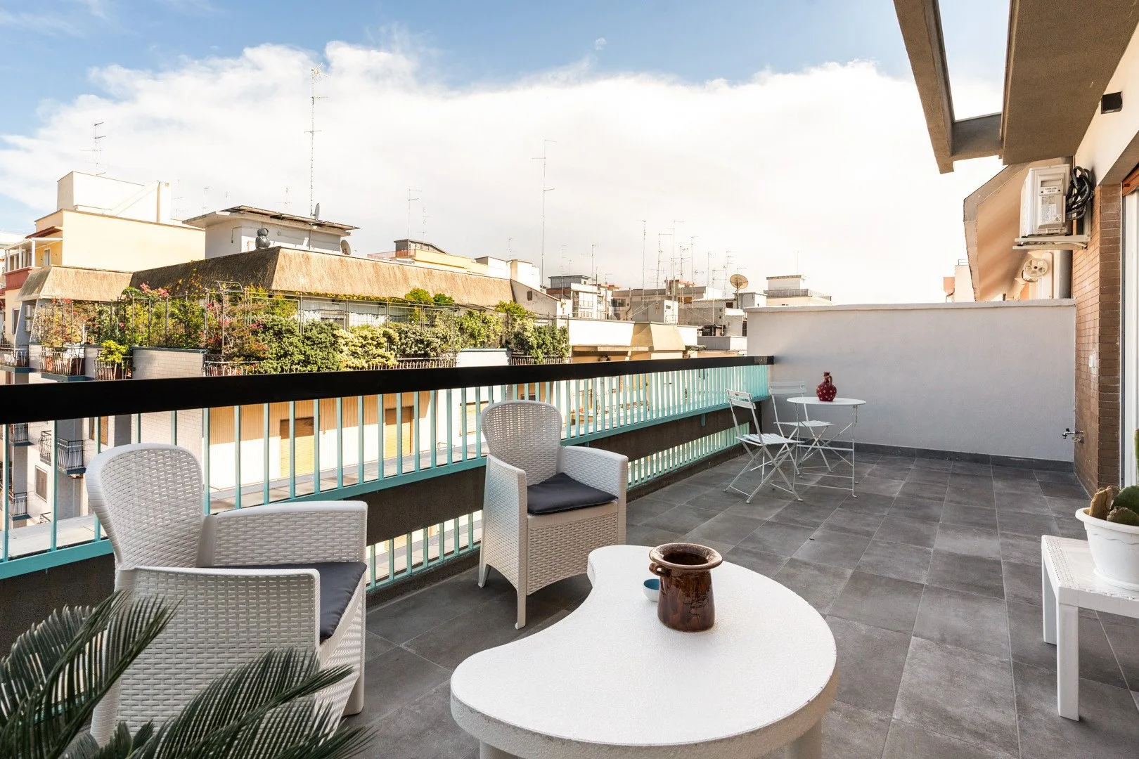 Una terraza en la azotea con asientos al aire libre, una mesa redonda y vistas a edificios cercanos.
