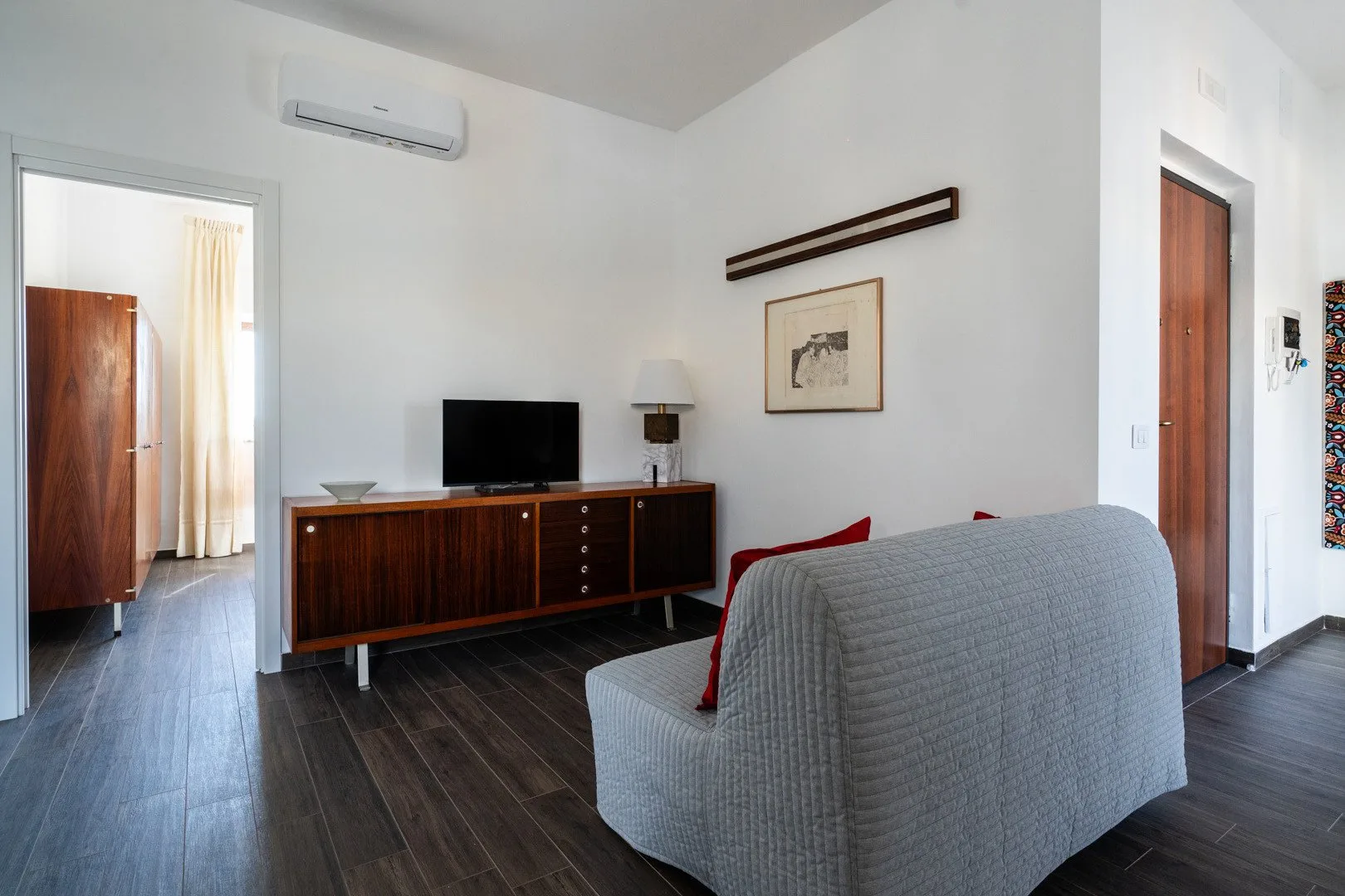 Una sala de estar con un televisor sobre un mueble de madera y asientos.