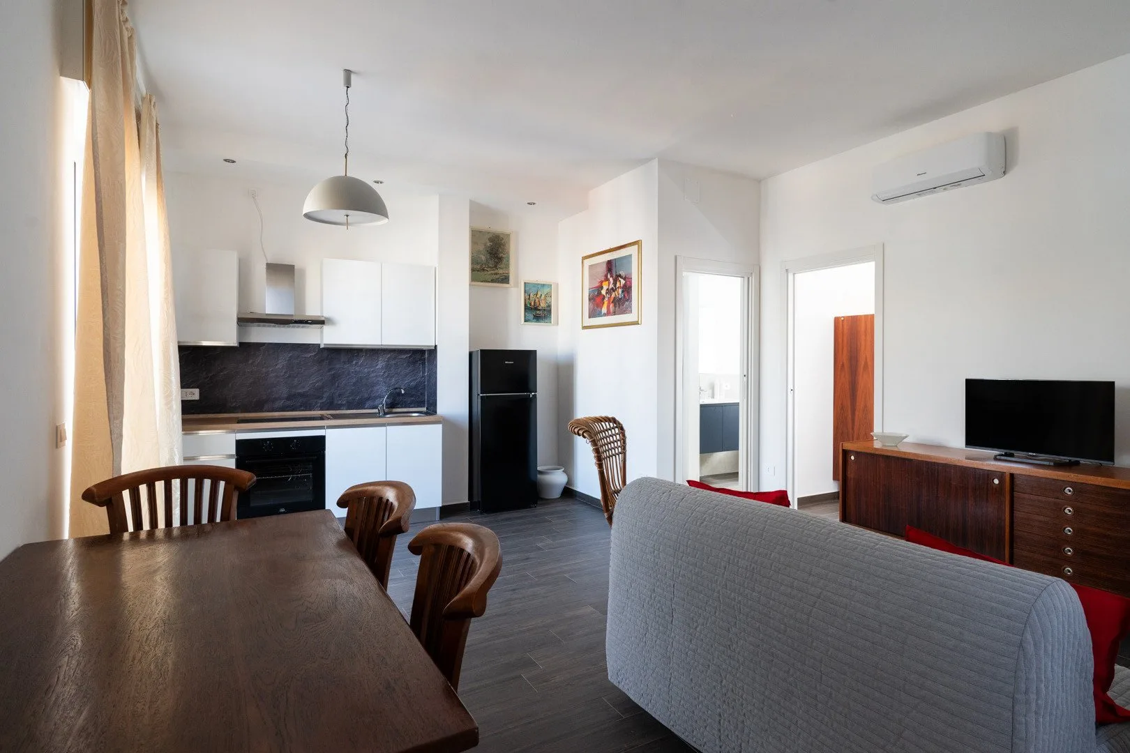 Una luminosa sala de estar y cocina abiertas, con mesa de comedor y televisor.