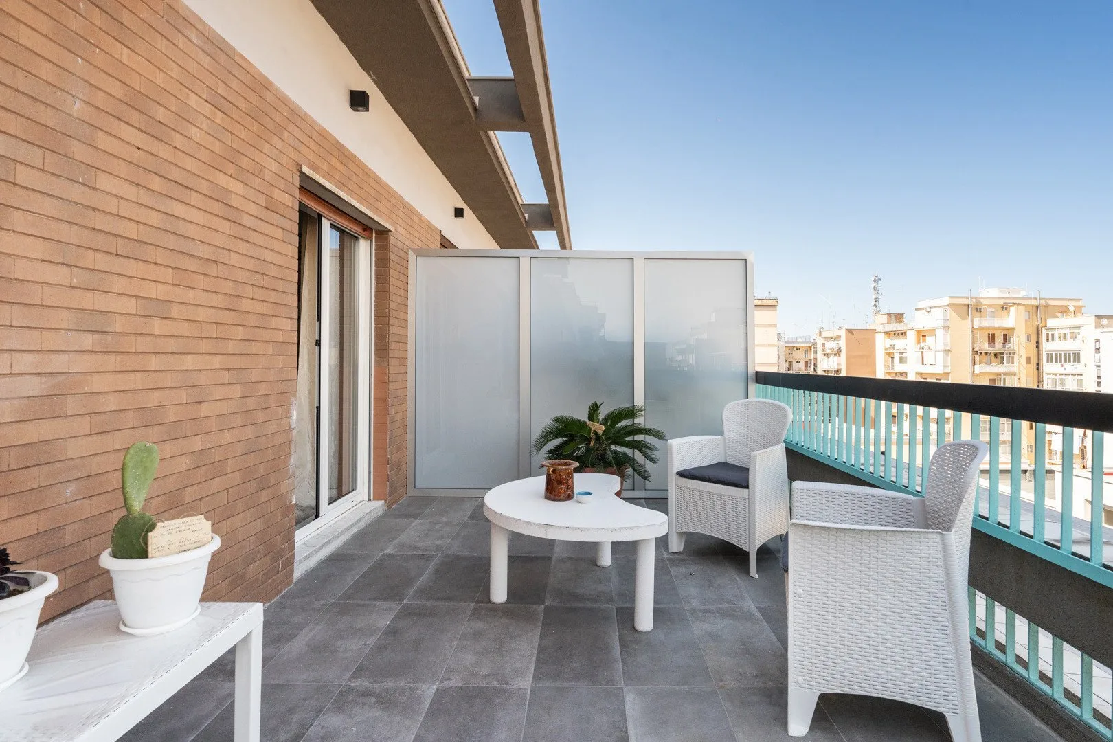Una zona de estar en un balcón con una mesa redonda y una planta en maceta.