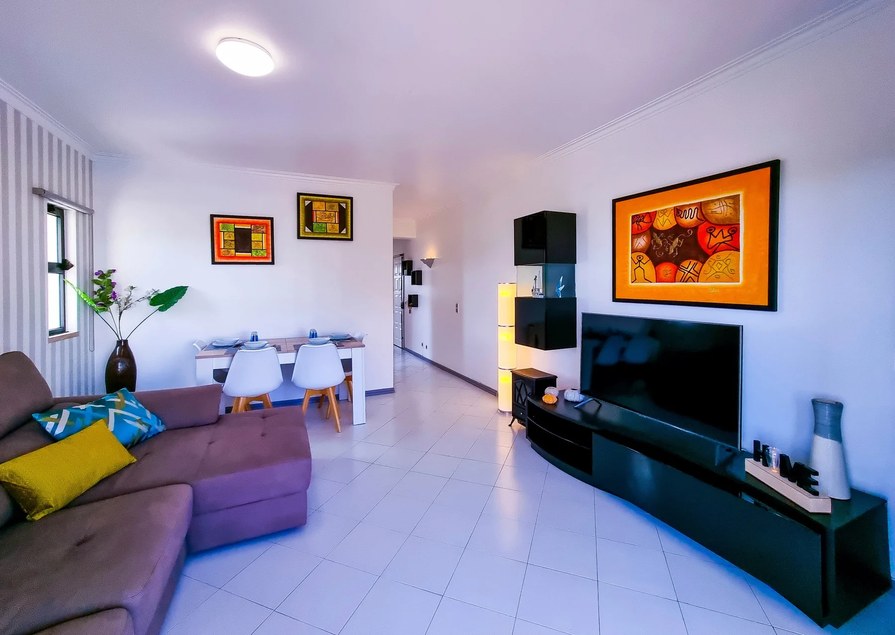 A living room with seating, a dining table, and a television.