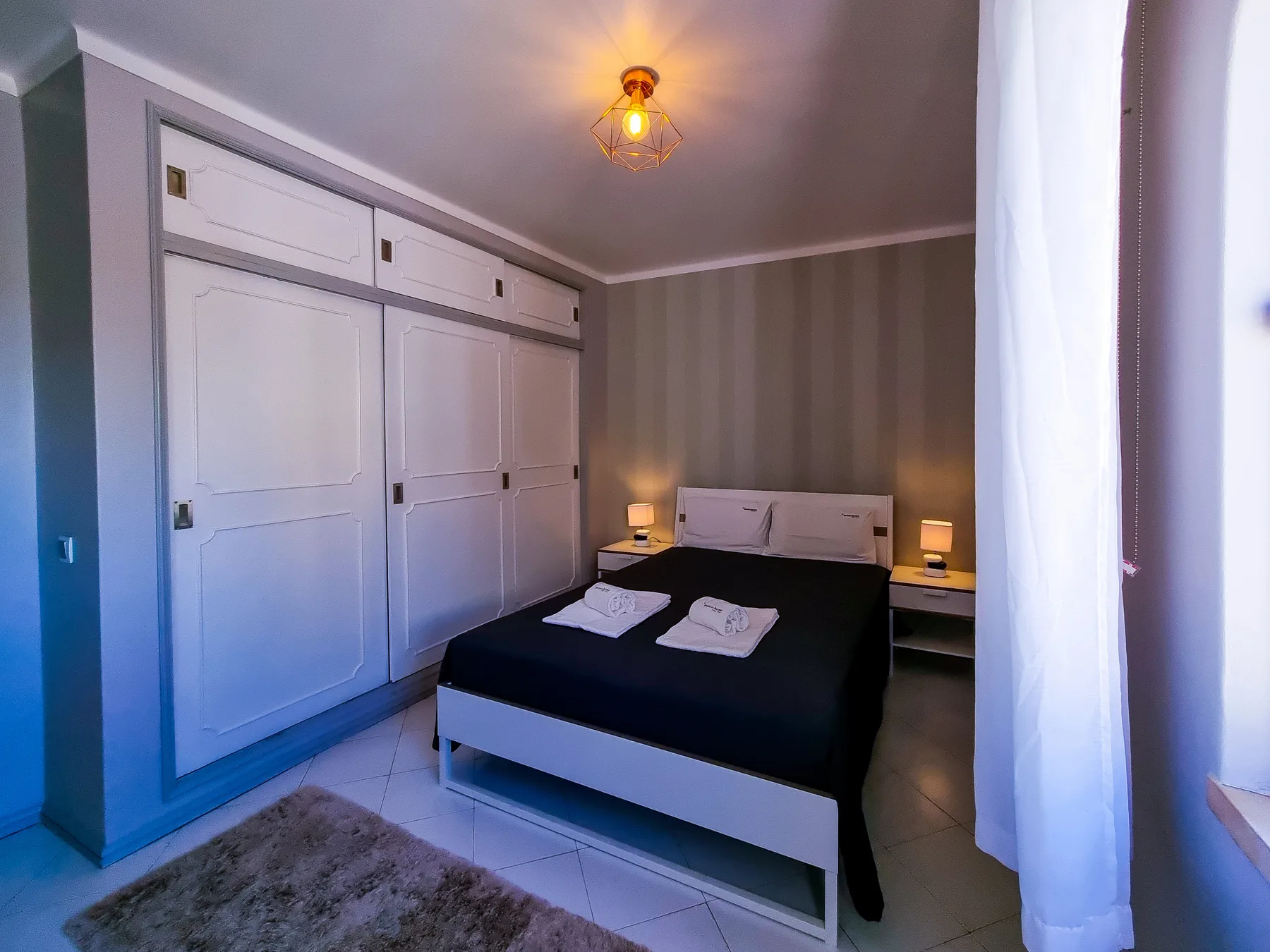 A bedroom with a double bed, built-in storage, and bedside lamps.