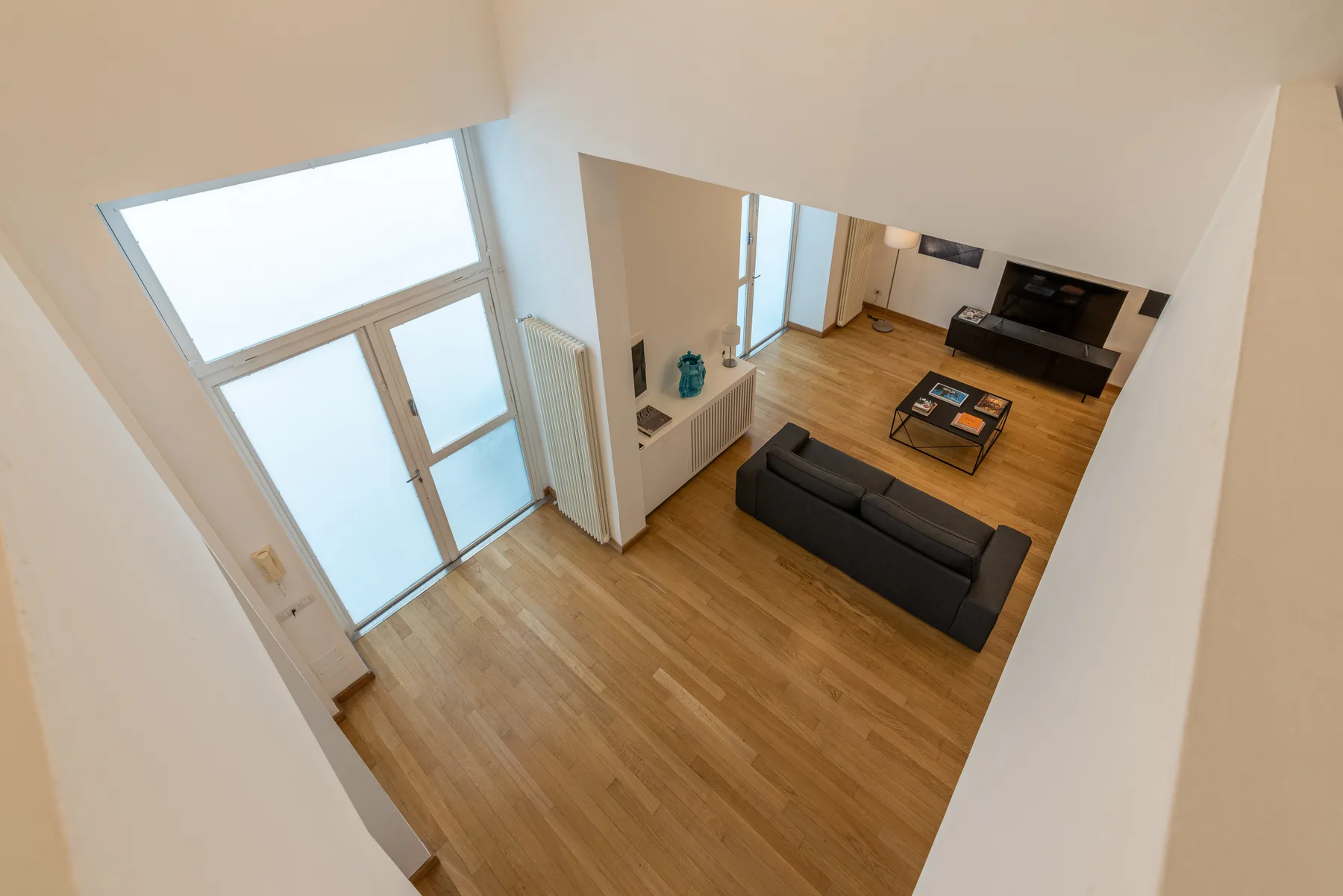 Una sala de estar con suelo de madera, asientos y un televisor.